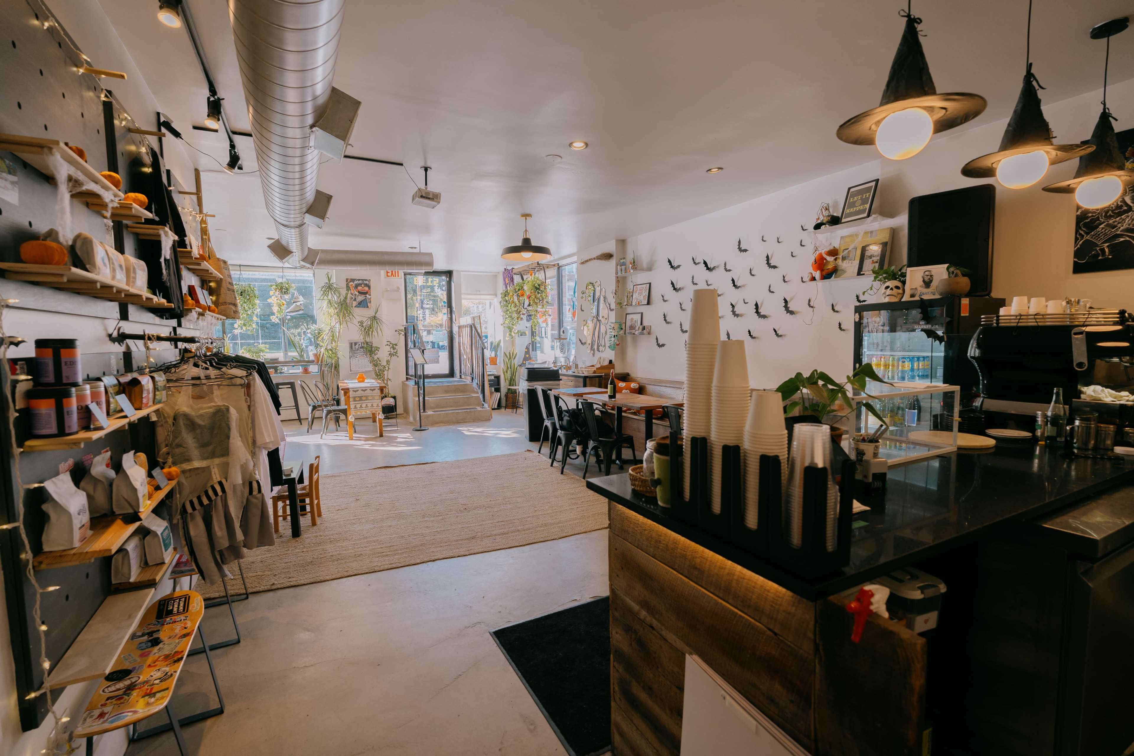 A cozy café featuring a blend of seating arrangements, decorative plants, and merchandise displayed on shelves.