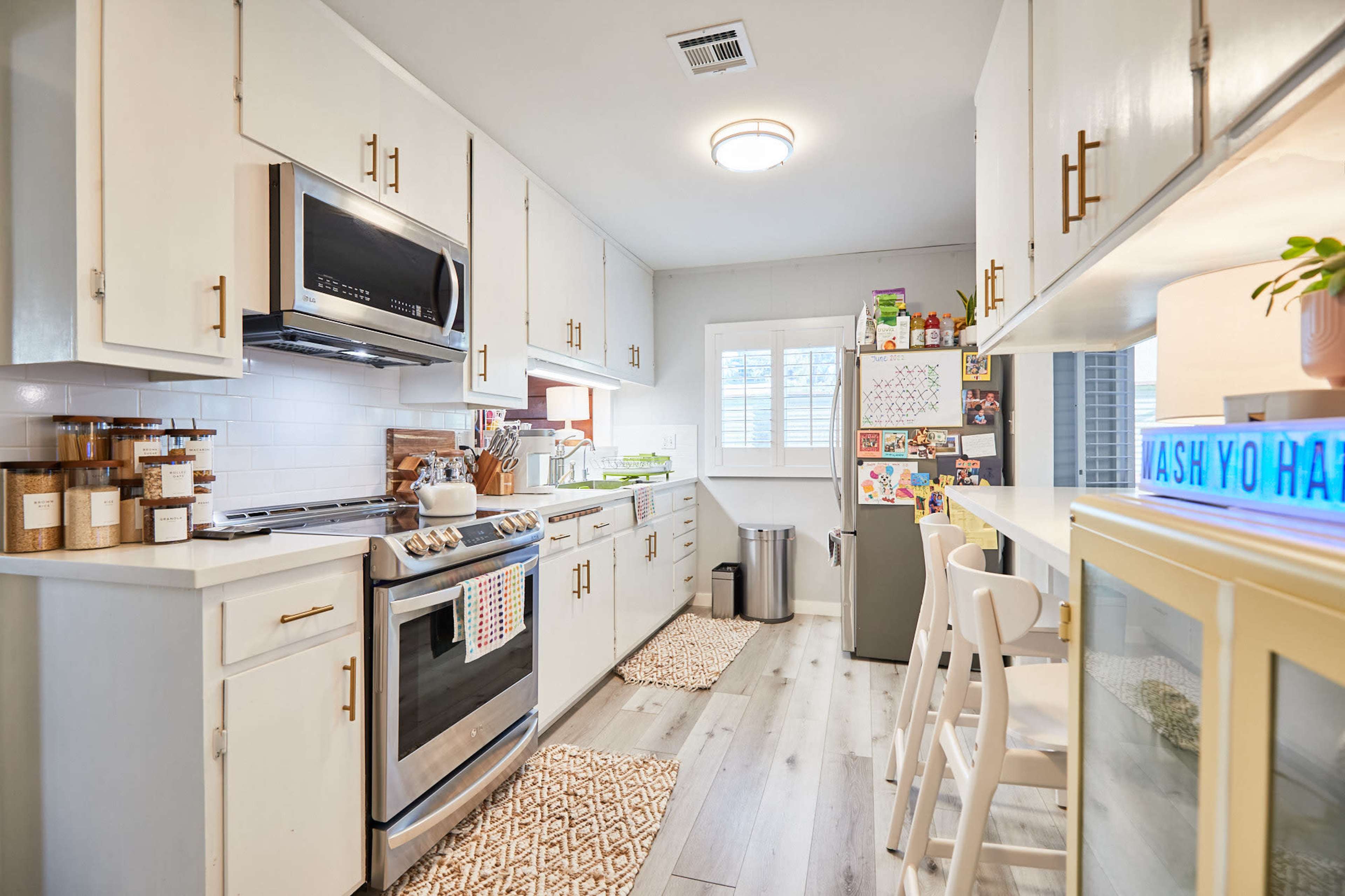 A modern kitchen with white cabinets, stainless steel appliances, and a small dining area featuring a table and chairs.
