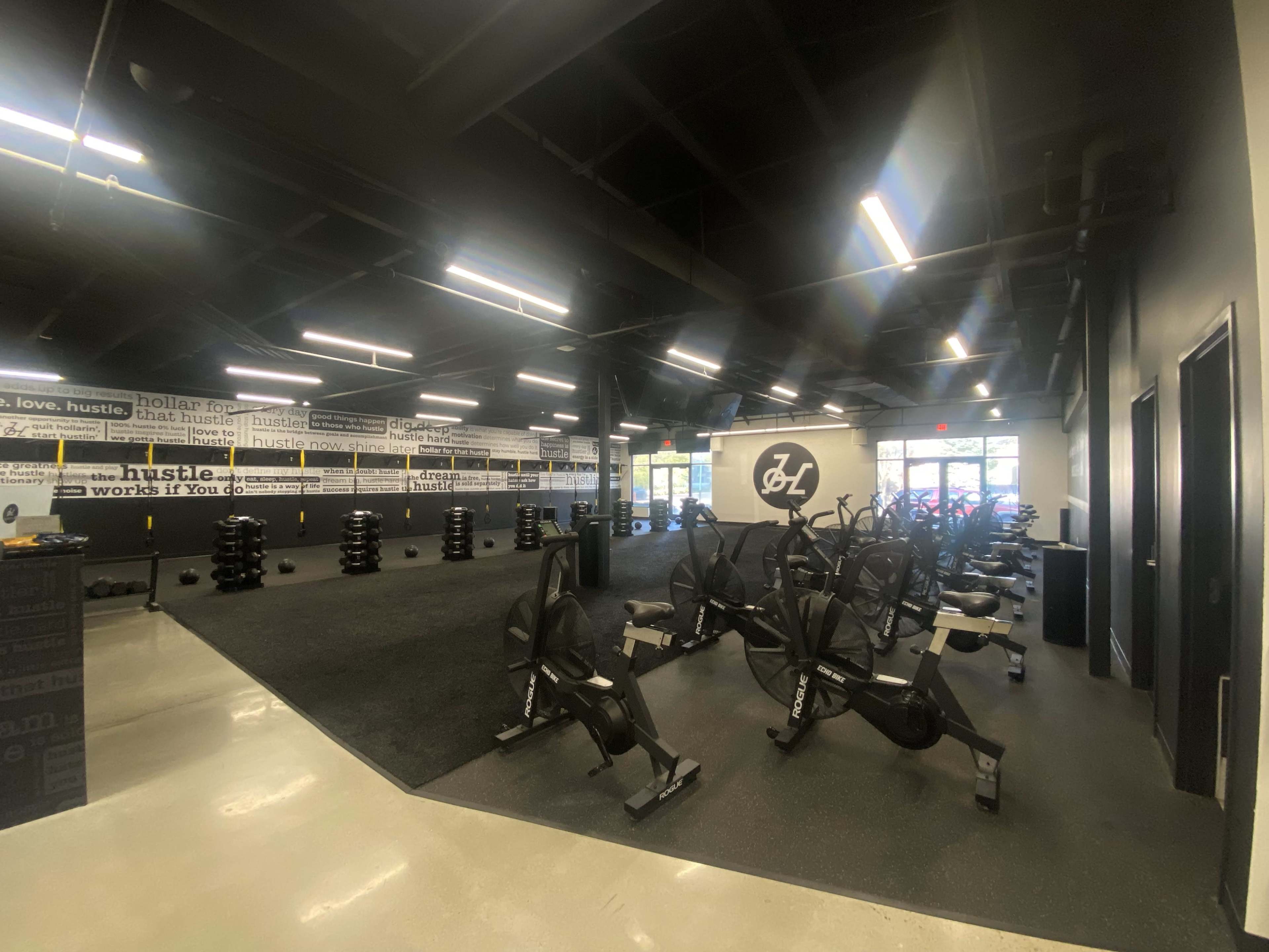 A modern gym interior with exercise bikes, weights, and motivational slogans on the walls.
