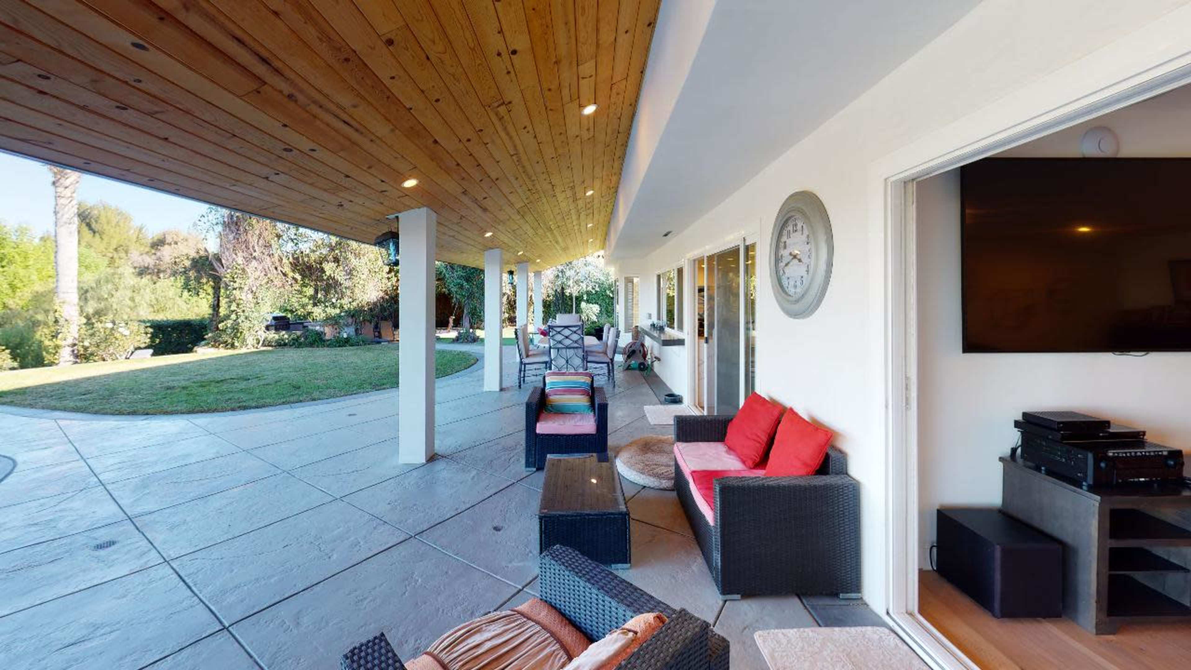 A spacious outdoor patio area with comfortable seating and a view of a manicured lawn.