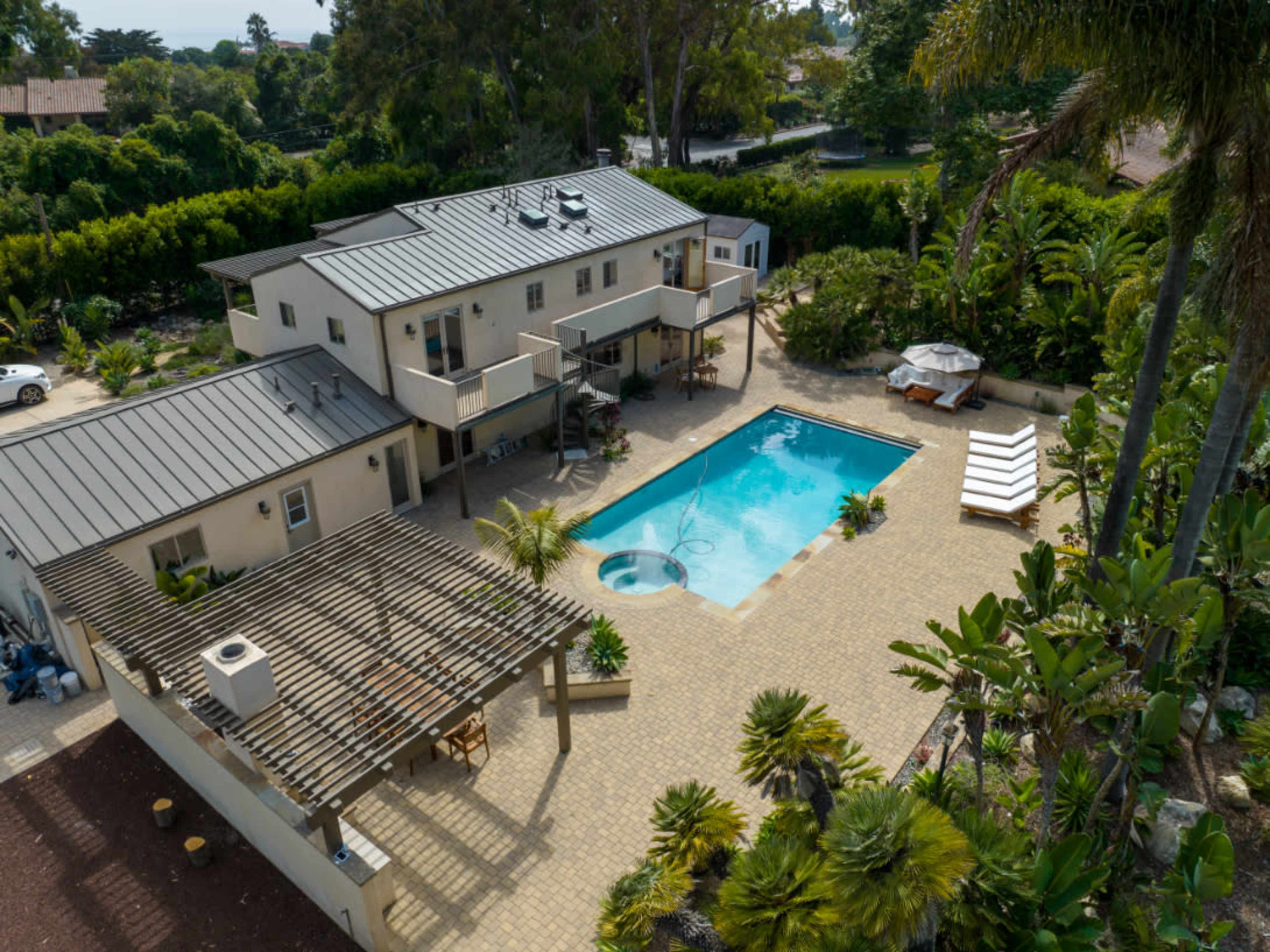 A modern house with a swimming pool, surrounded by landscaped gardens and outdoor seating areas.