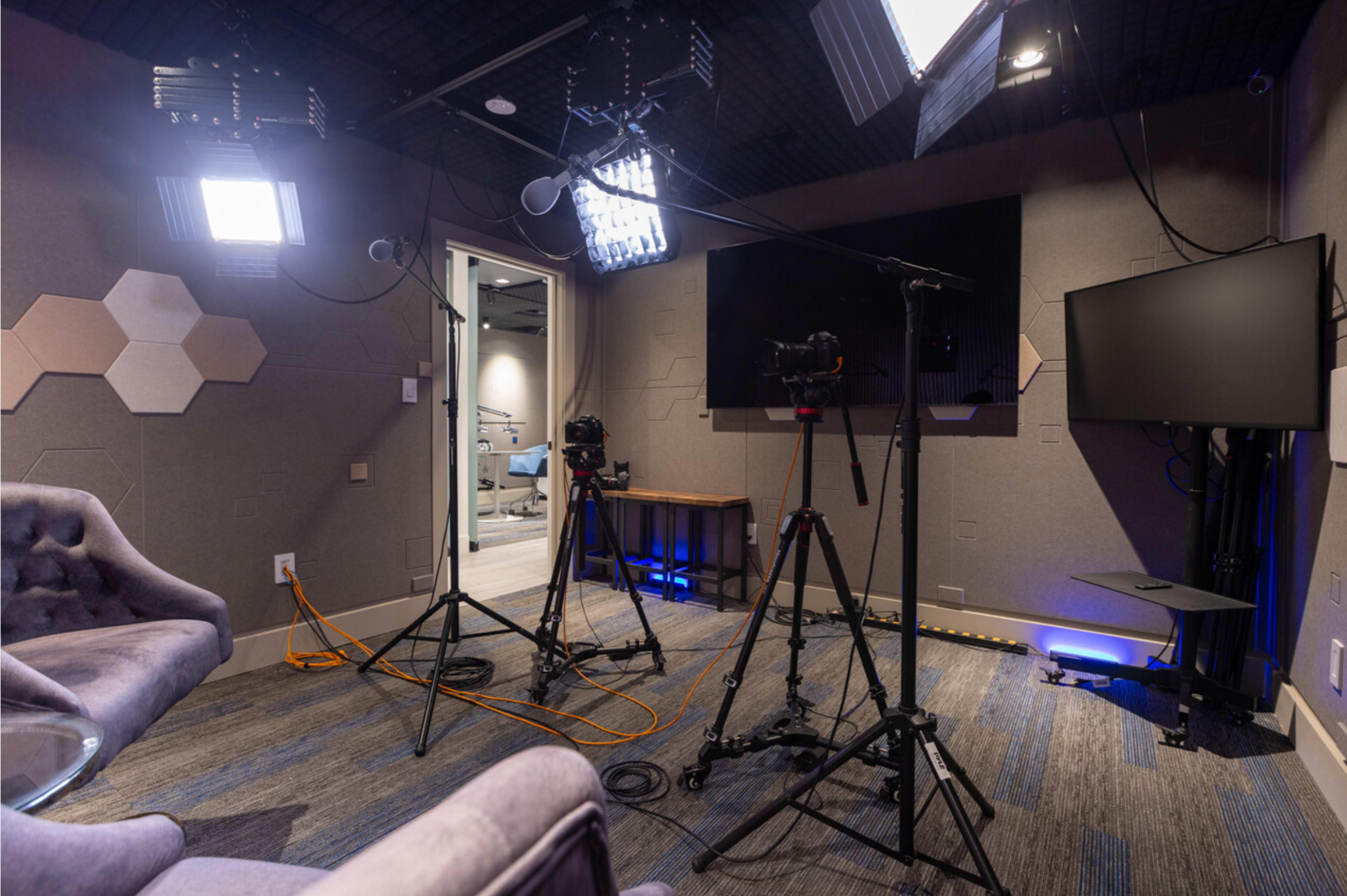 A recording studio with cameras, lights, and a sofa, designed for video production.