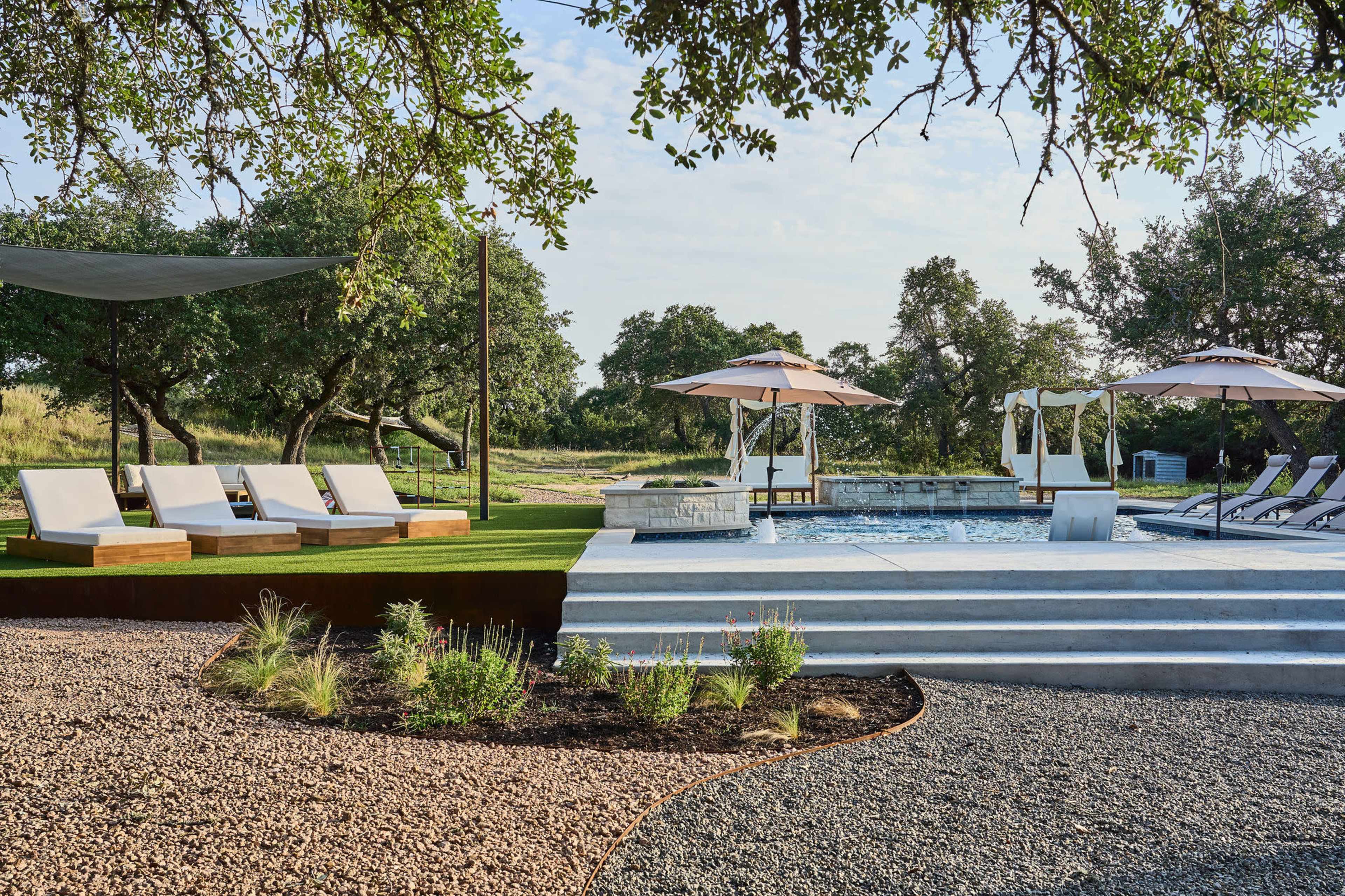 The image shows a landscaped outdoor area featuring a swimming pool, lounge chairs, and a swing surrounded by trees and decorative plants.