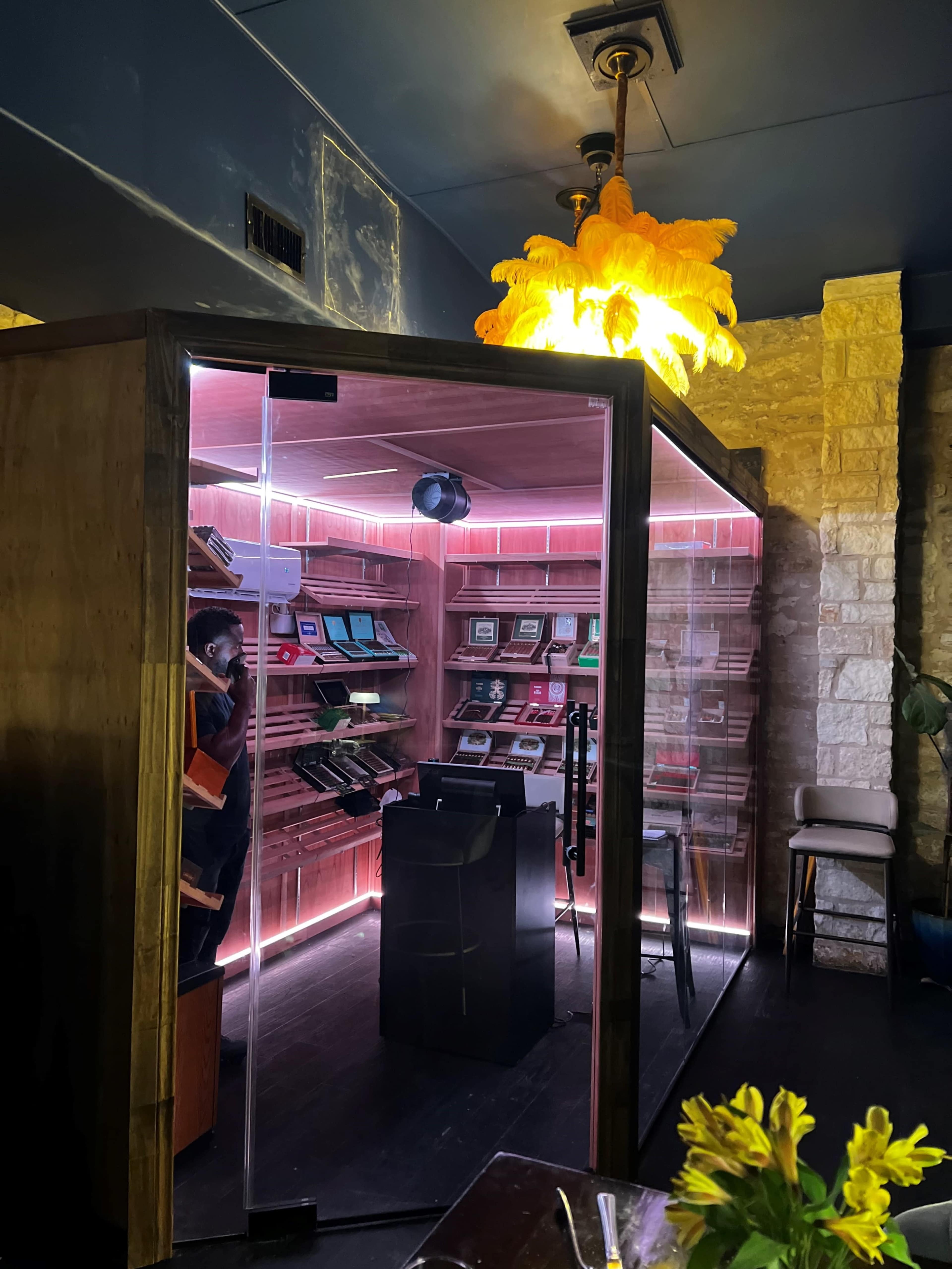 The image shows a modern bookshelf booth illuminated with pink lighting, containing various books, and a large pendant lamp hanging above it.