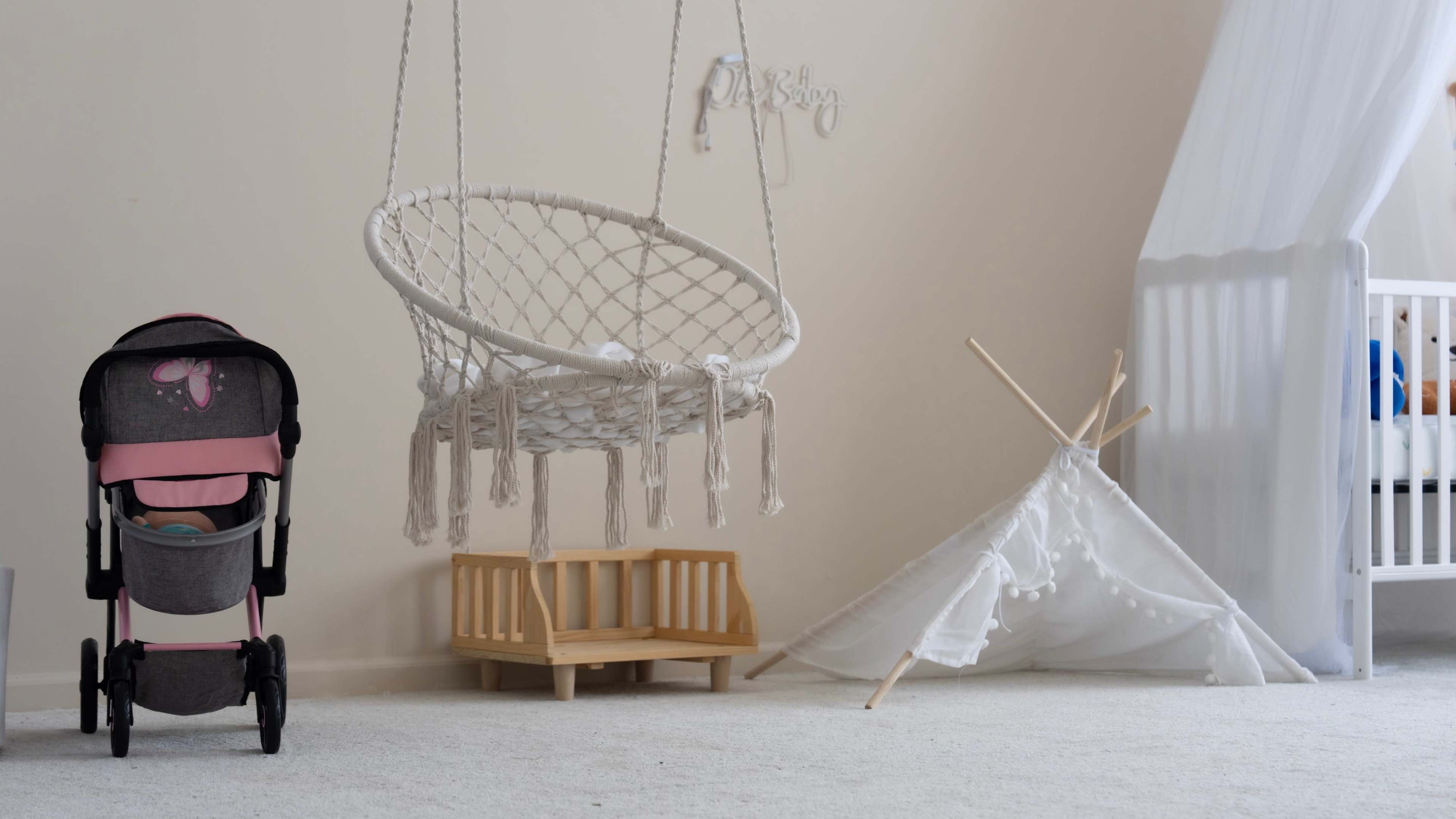 The image shows a cozy indoor space featuring a hanging macrame chair, a small wooden bench, and a white teepee tent in a corner.