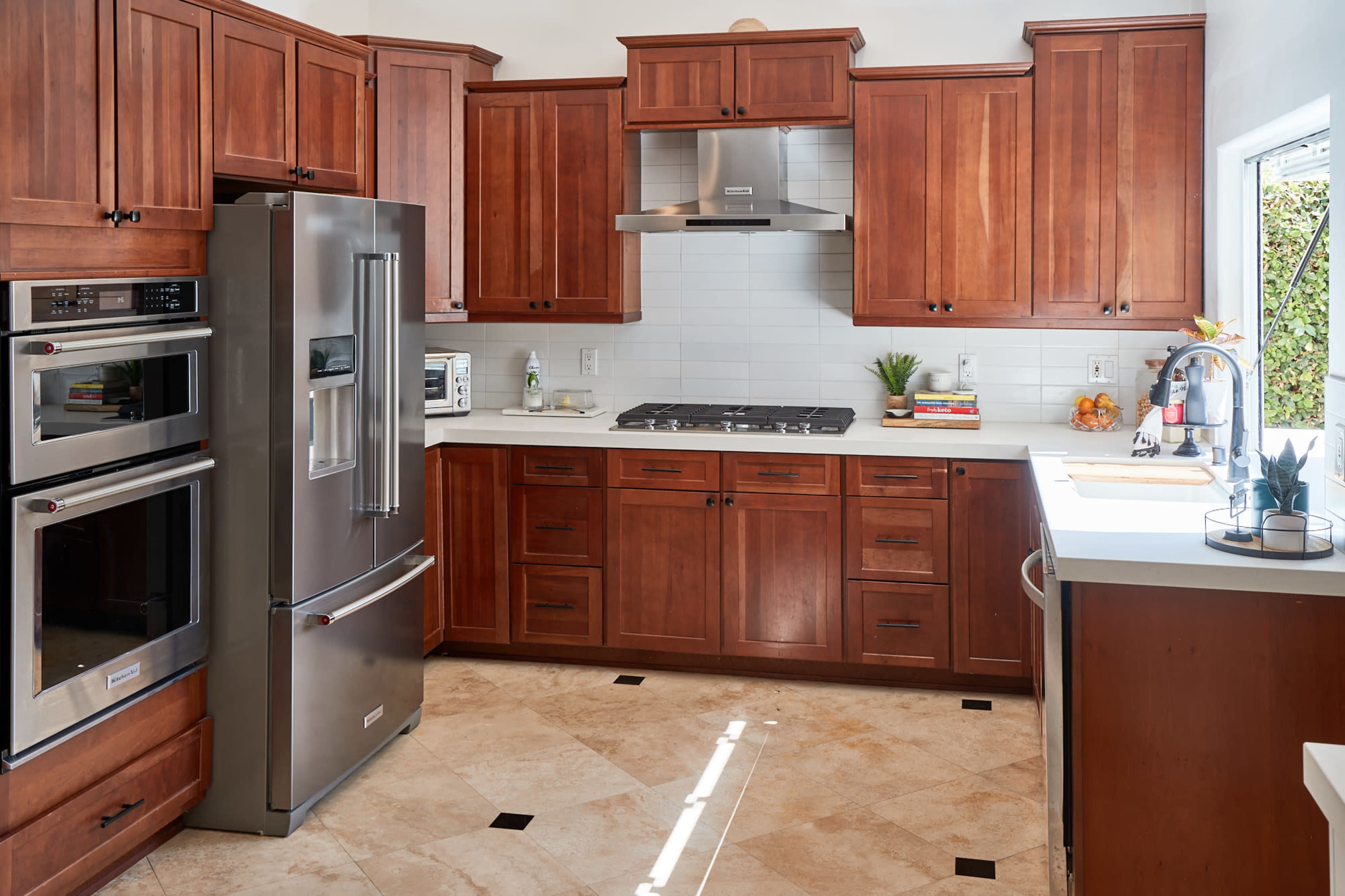 A kitchen with wooden cabinetry, stainless steel appliances, and a tiled floor.