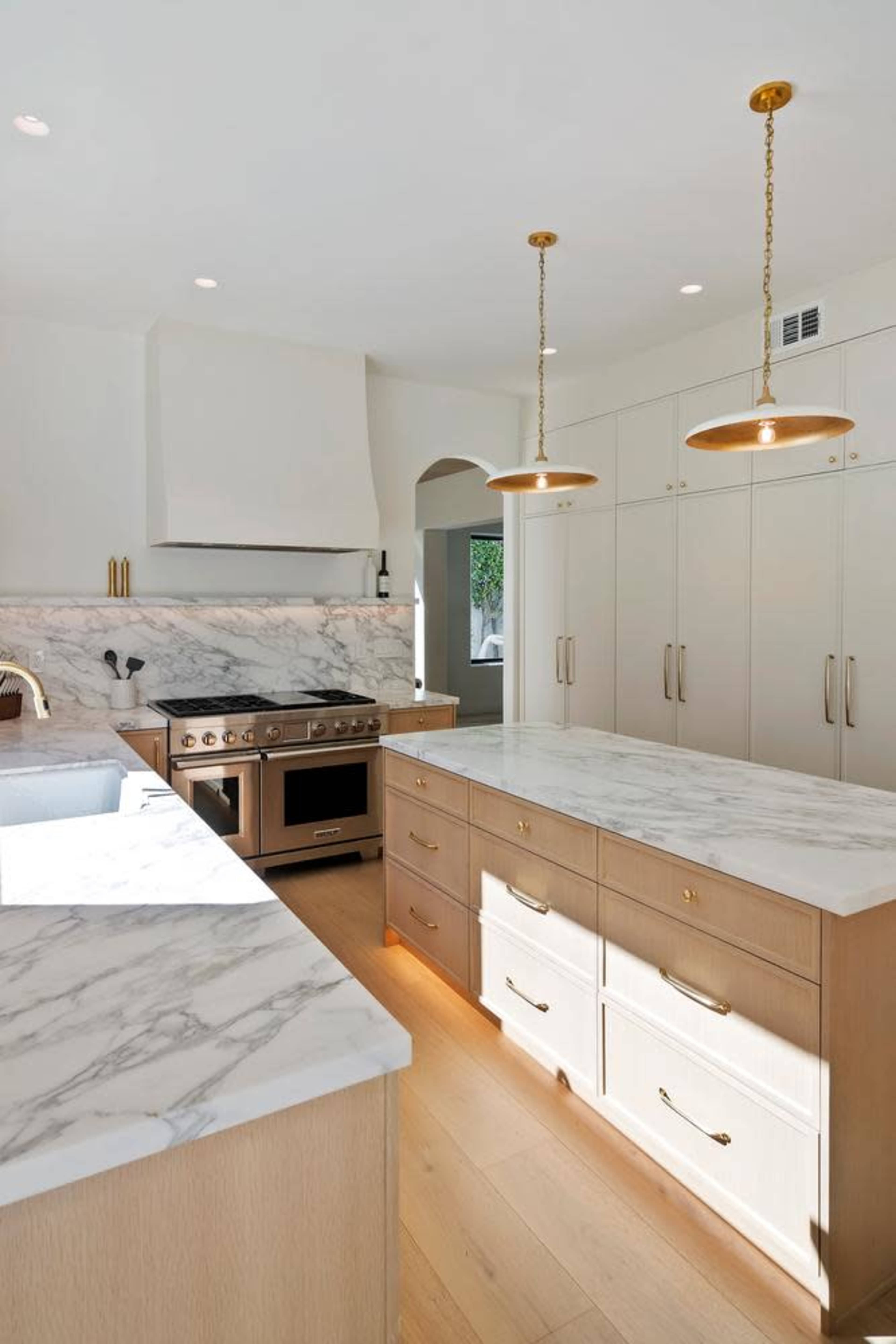 The kitchen features a marble countertop island, a large stove, and stylish pendant lights.
