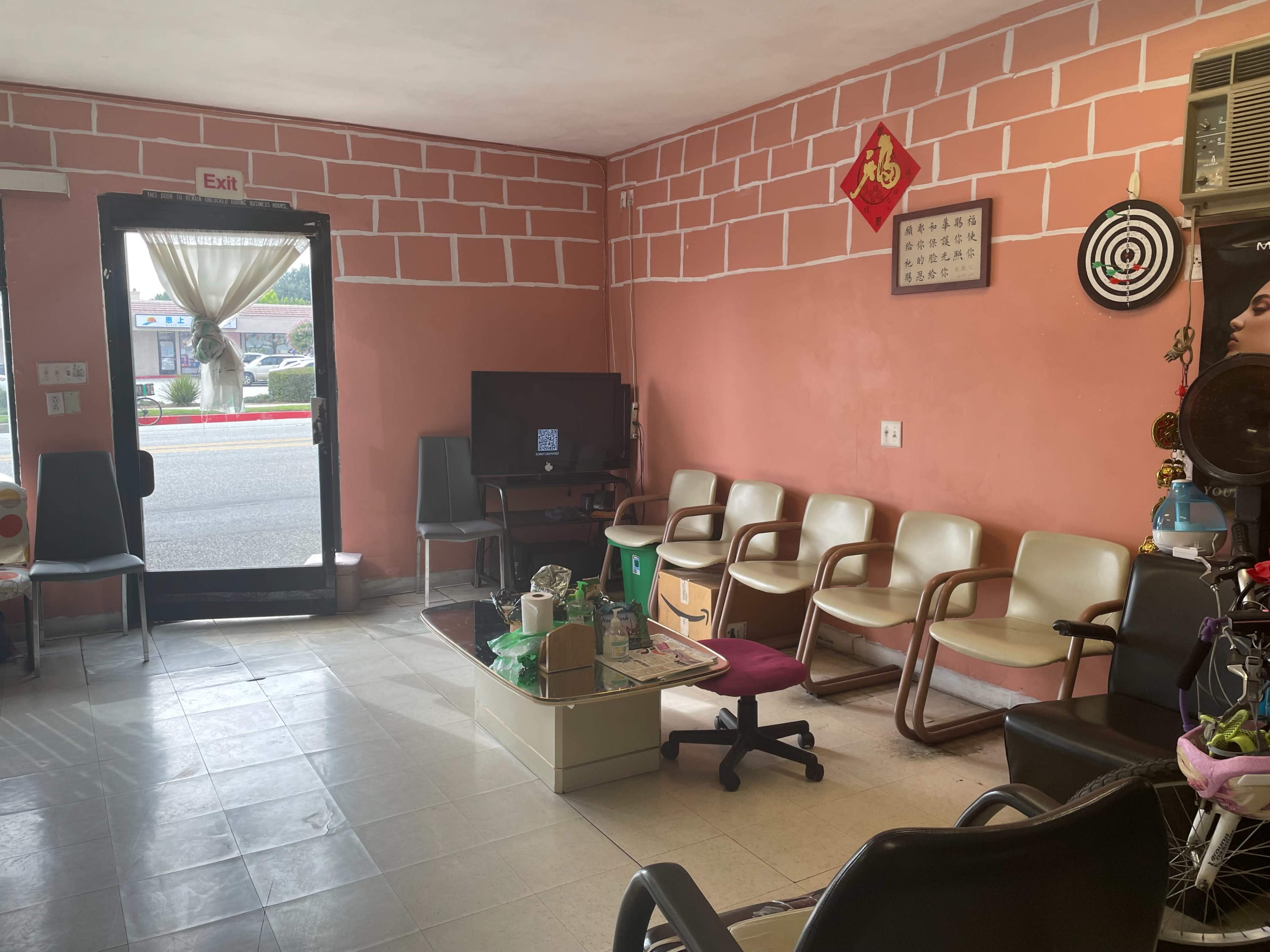 The interior of a waiting area with several chairs, a television, and a door leading outside.