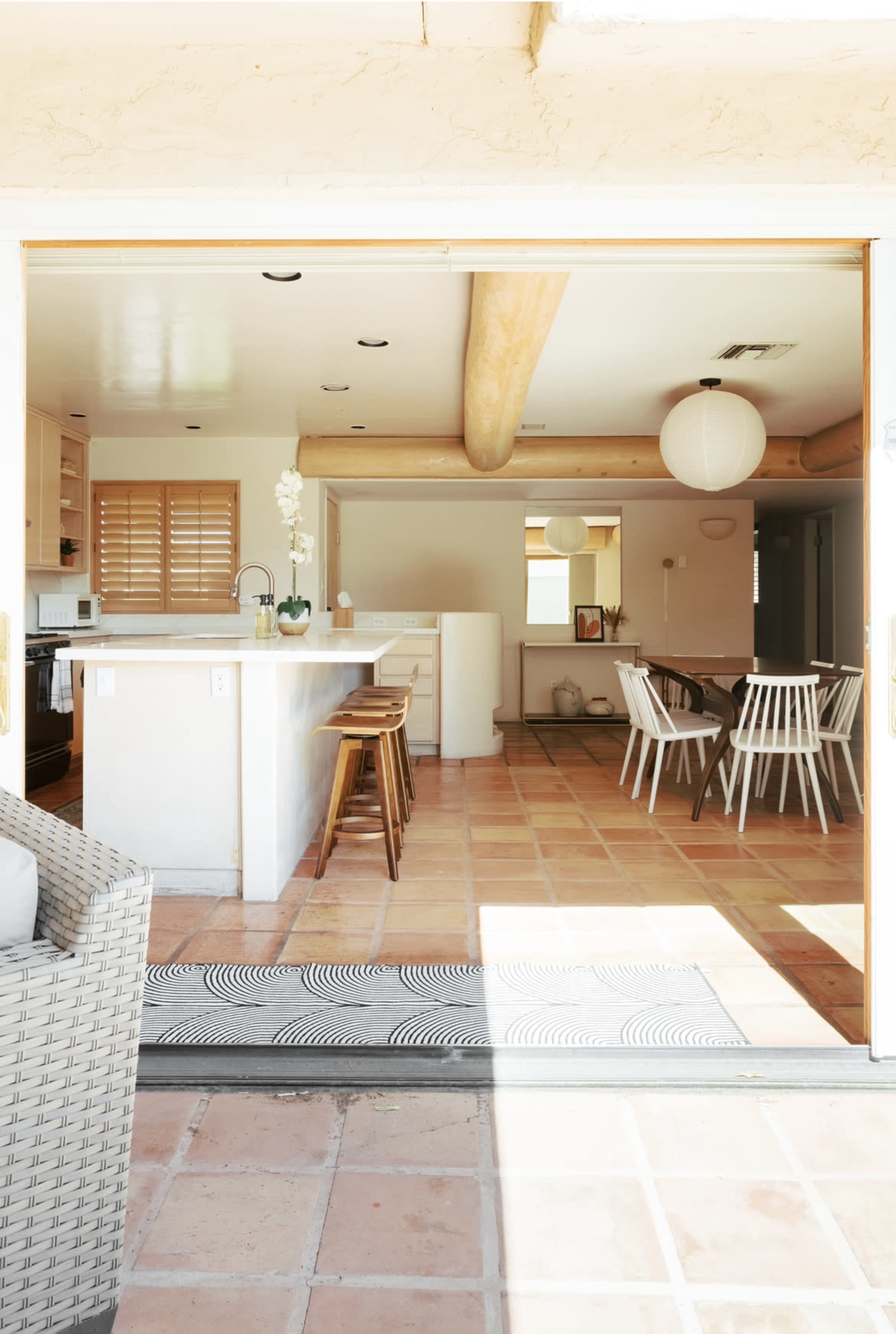 The image shows a spacious open-concept kitchen and dining area with tile flooring, visible through a large sliding door.