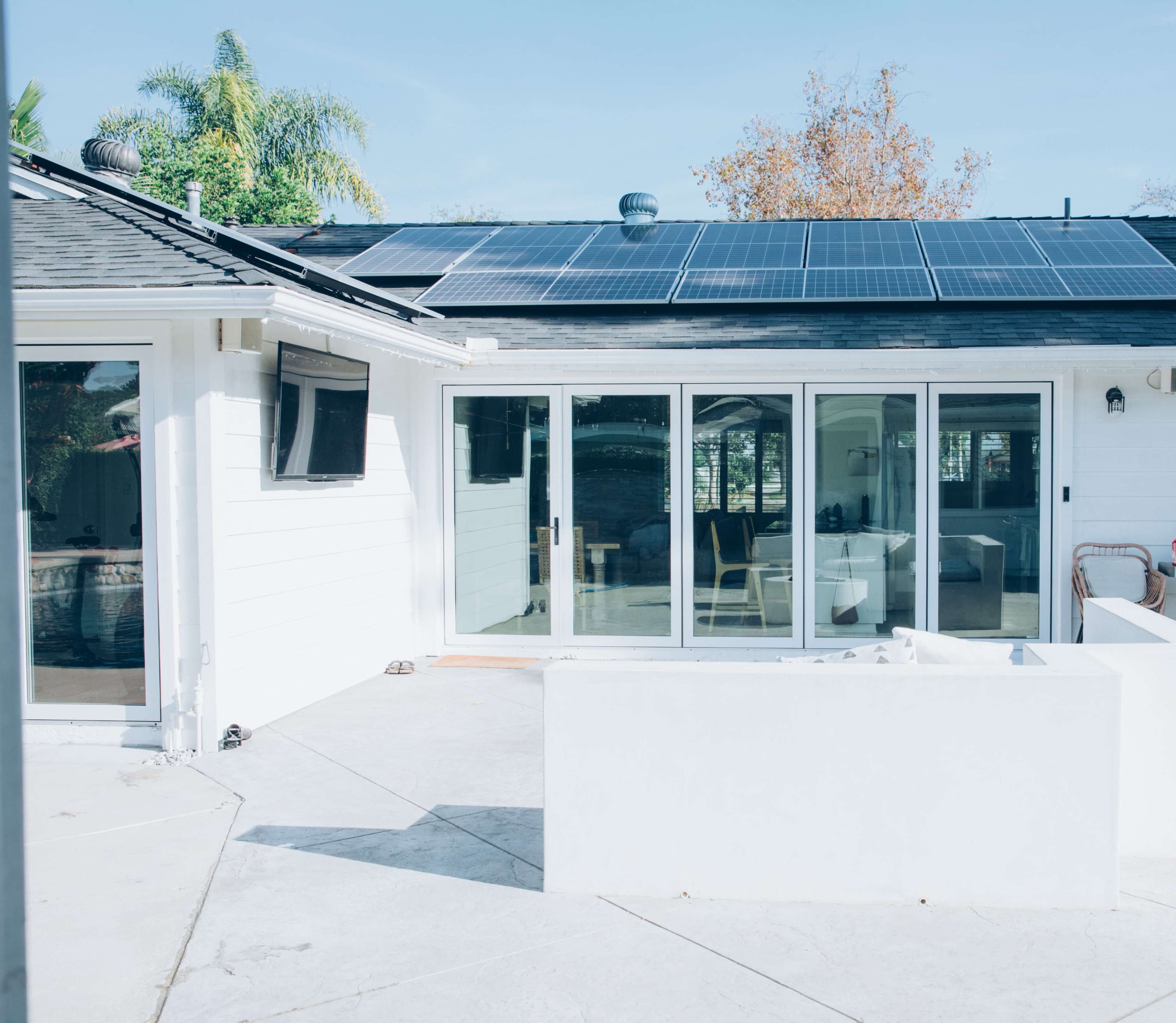 A modern home with solar panels on the roof and a spacious outdoor patio area.