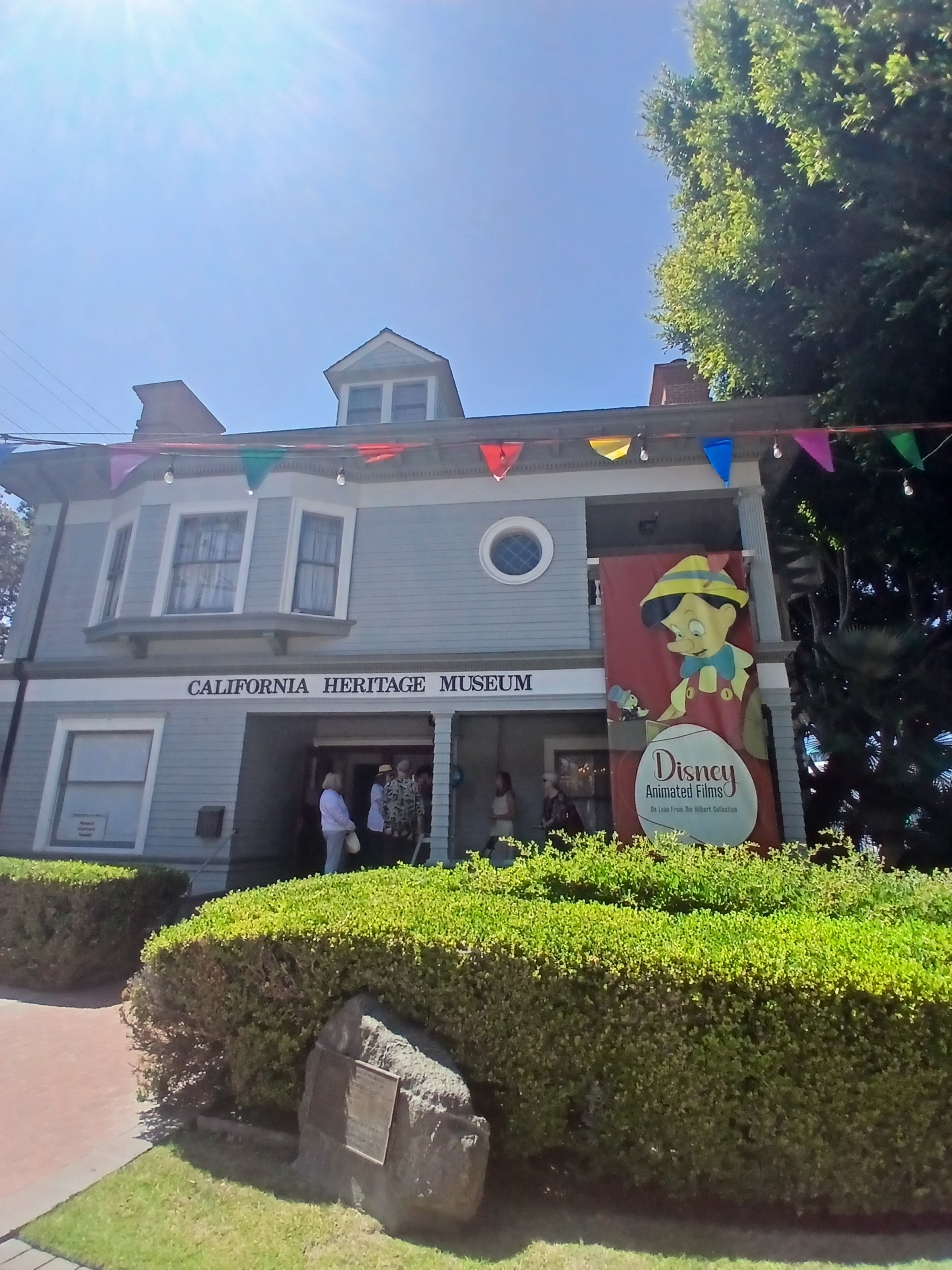 The California Heritage Museum features a large banner displaying Disney's animated characters and is decorated with colorful bunting.