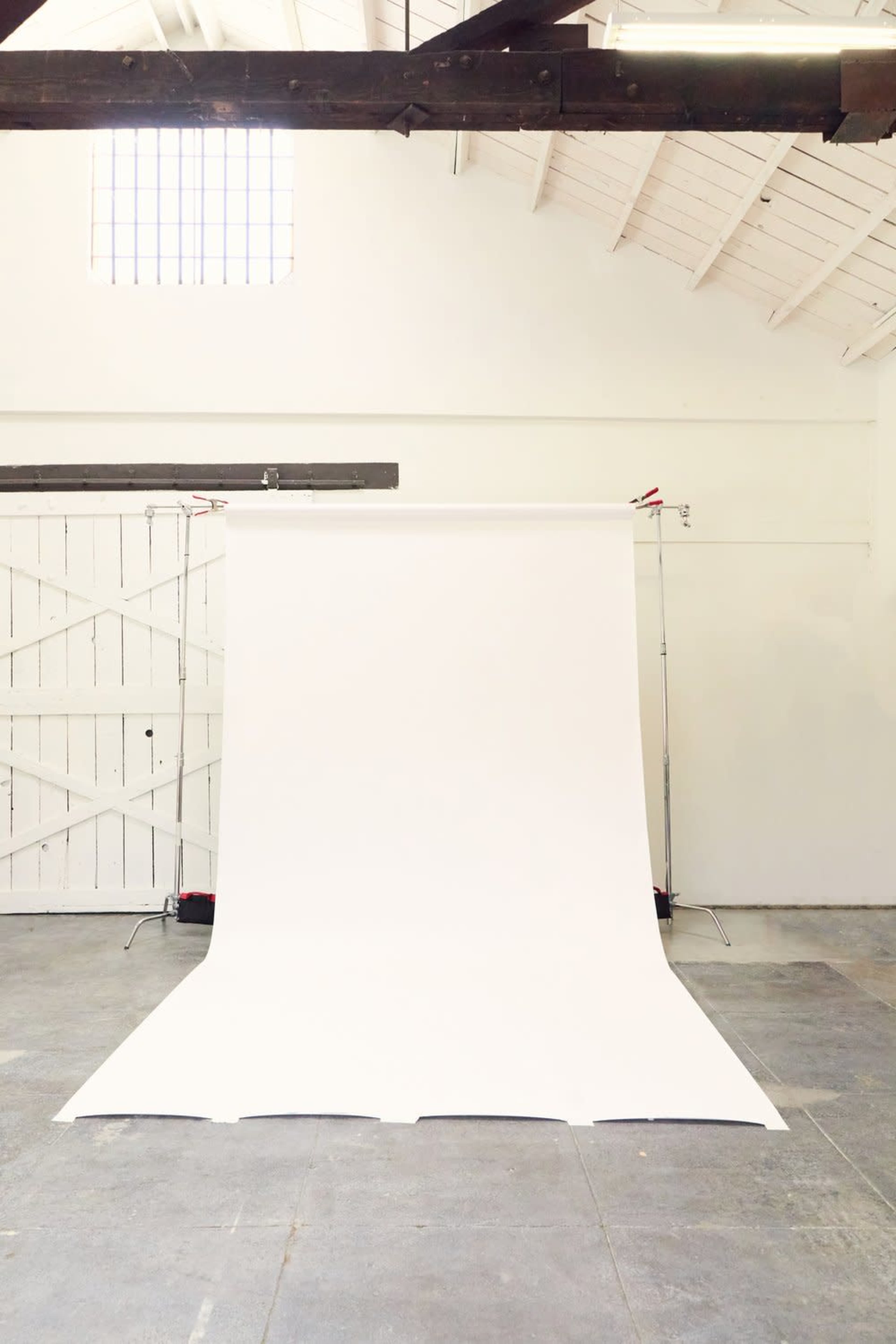 The image shows a spacious indoor studio with a white backdrop setup for photography.