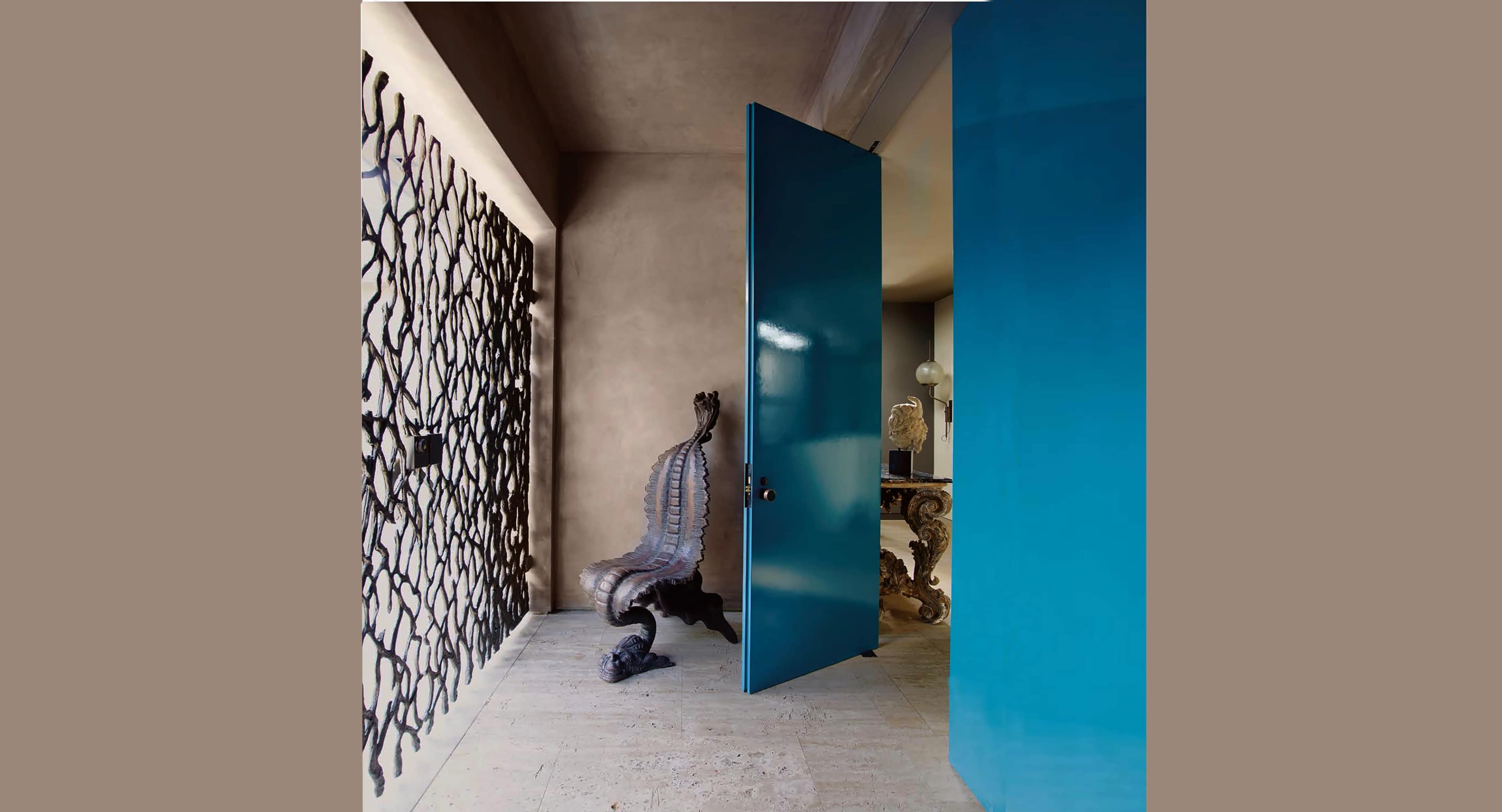 The image shows a brightly colored turquoise door partially open in a room with a decorative black metal screen and an ornate chair.