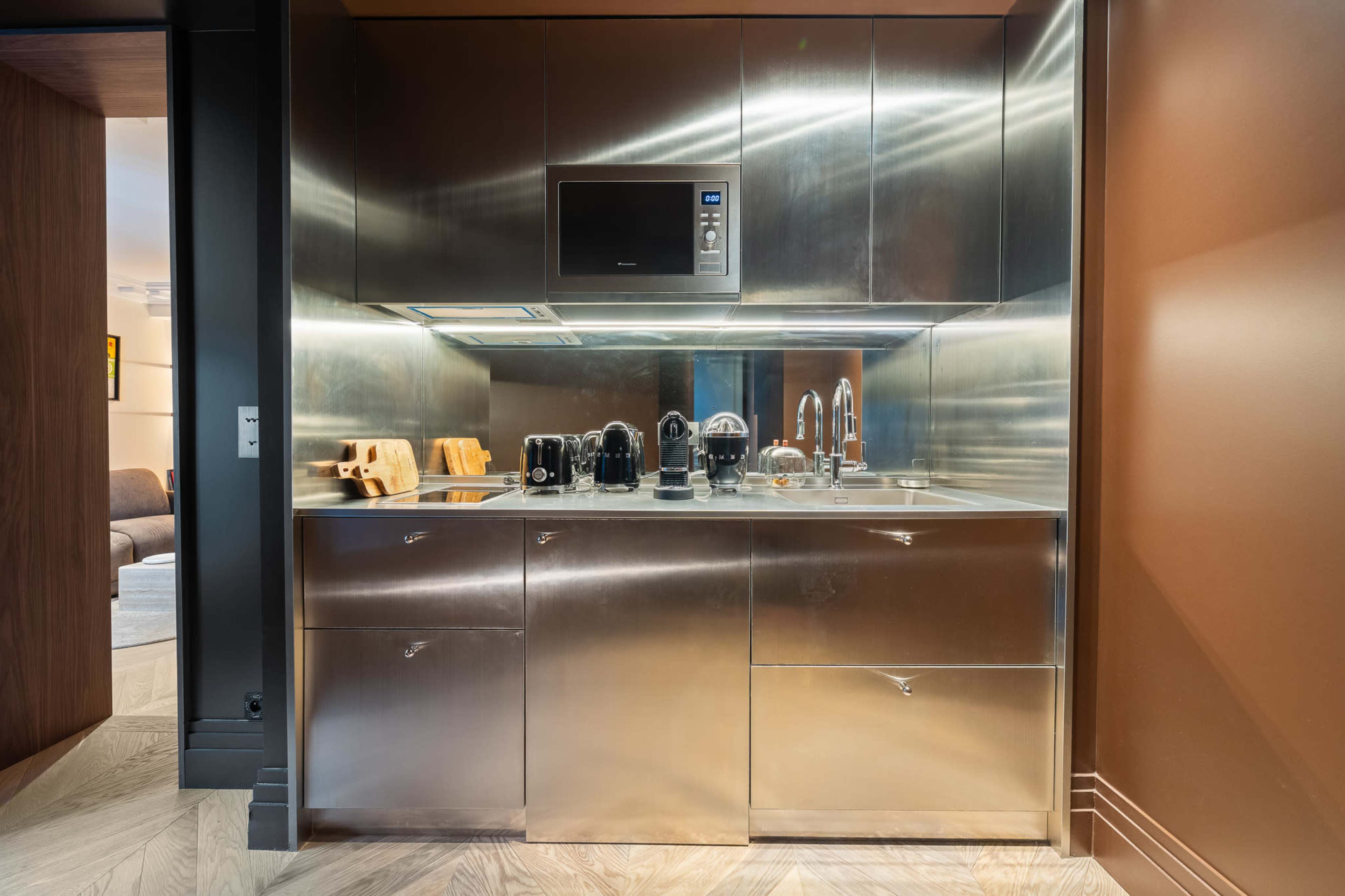 The image shows a modern kitchen with stainless steel cabinets, a microwave, and various kitchen appliances arranged on a countertop.