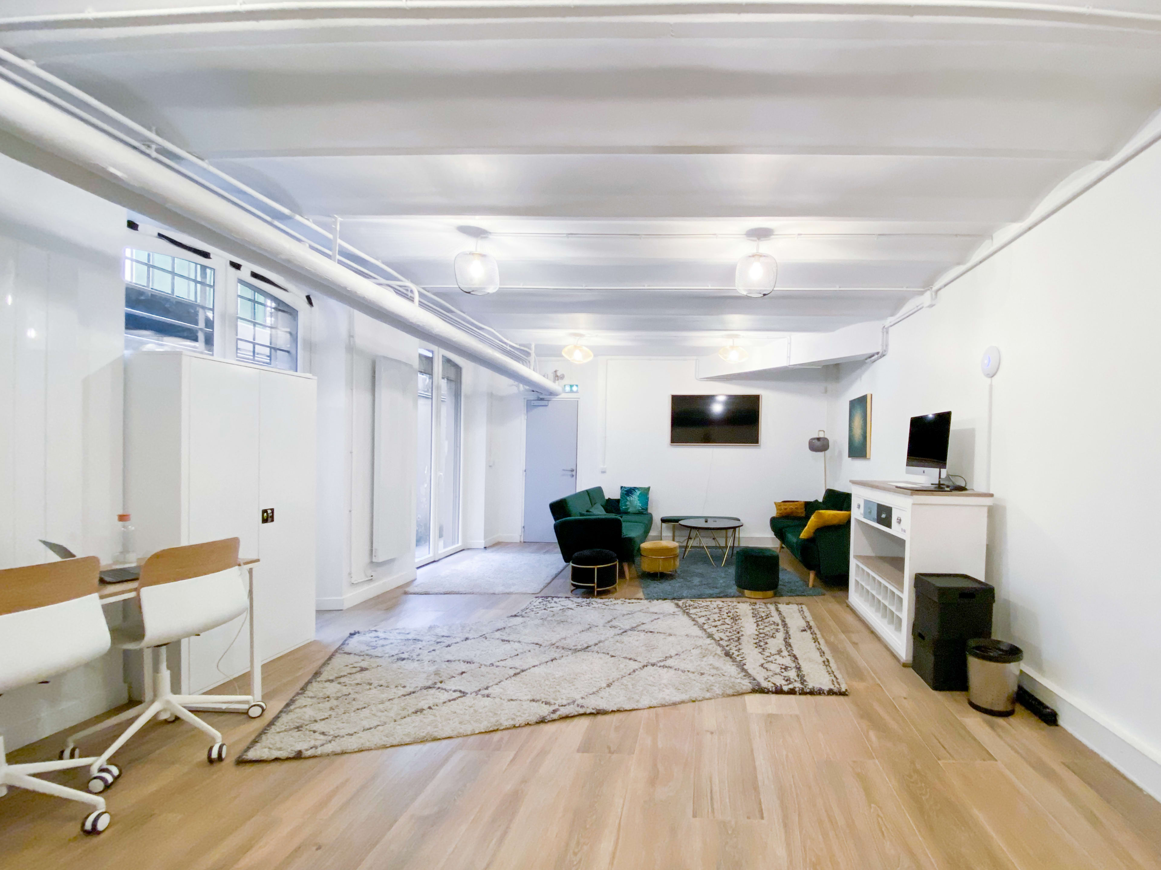 A spacious, modern living area with a seating arrangement, a coffee table, a rug, and large windows allowing natural light.