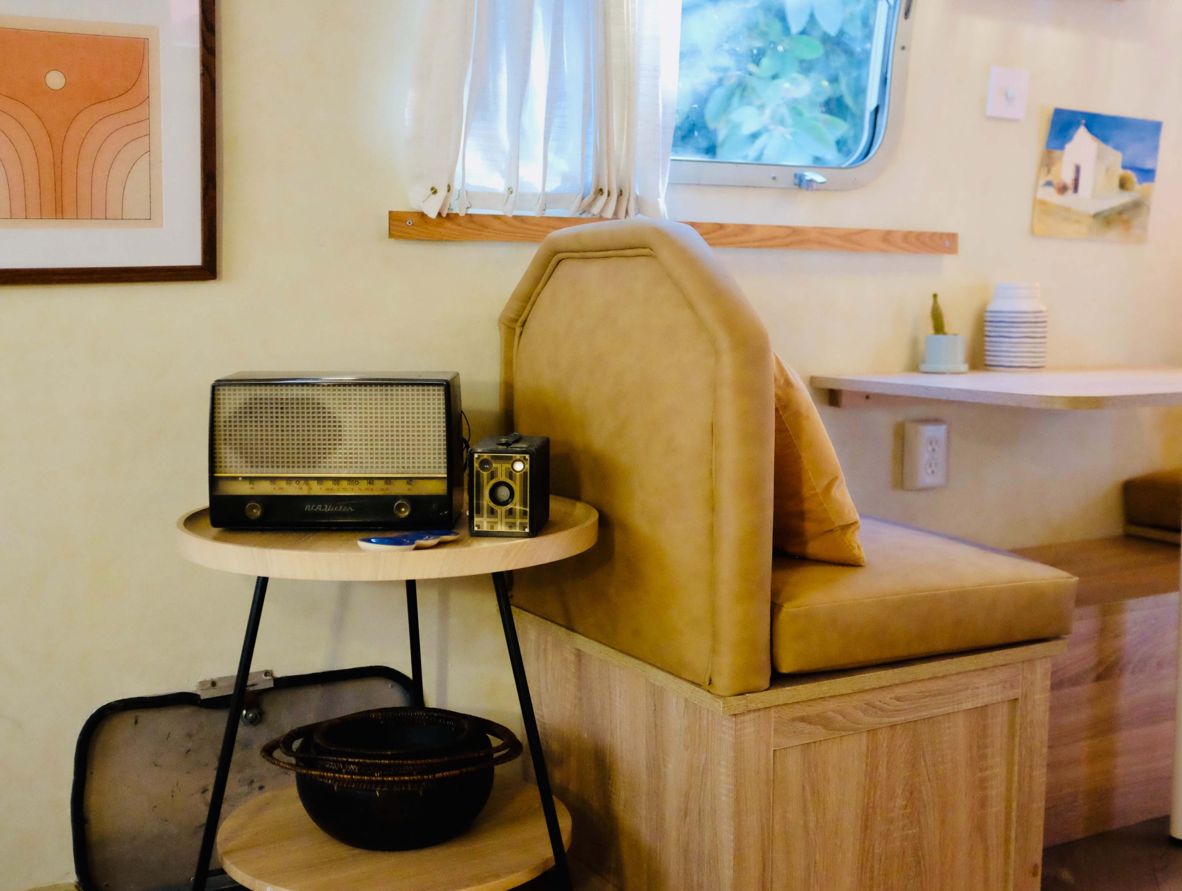 The image shows a cozy interior featuring a retro radio on a round side table next to a cushioned seating area and a light-colored wooden surface.