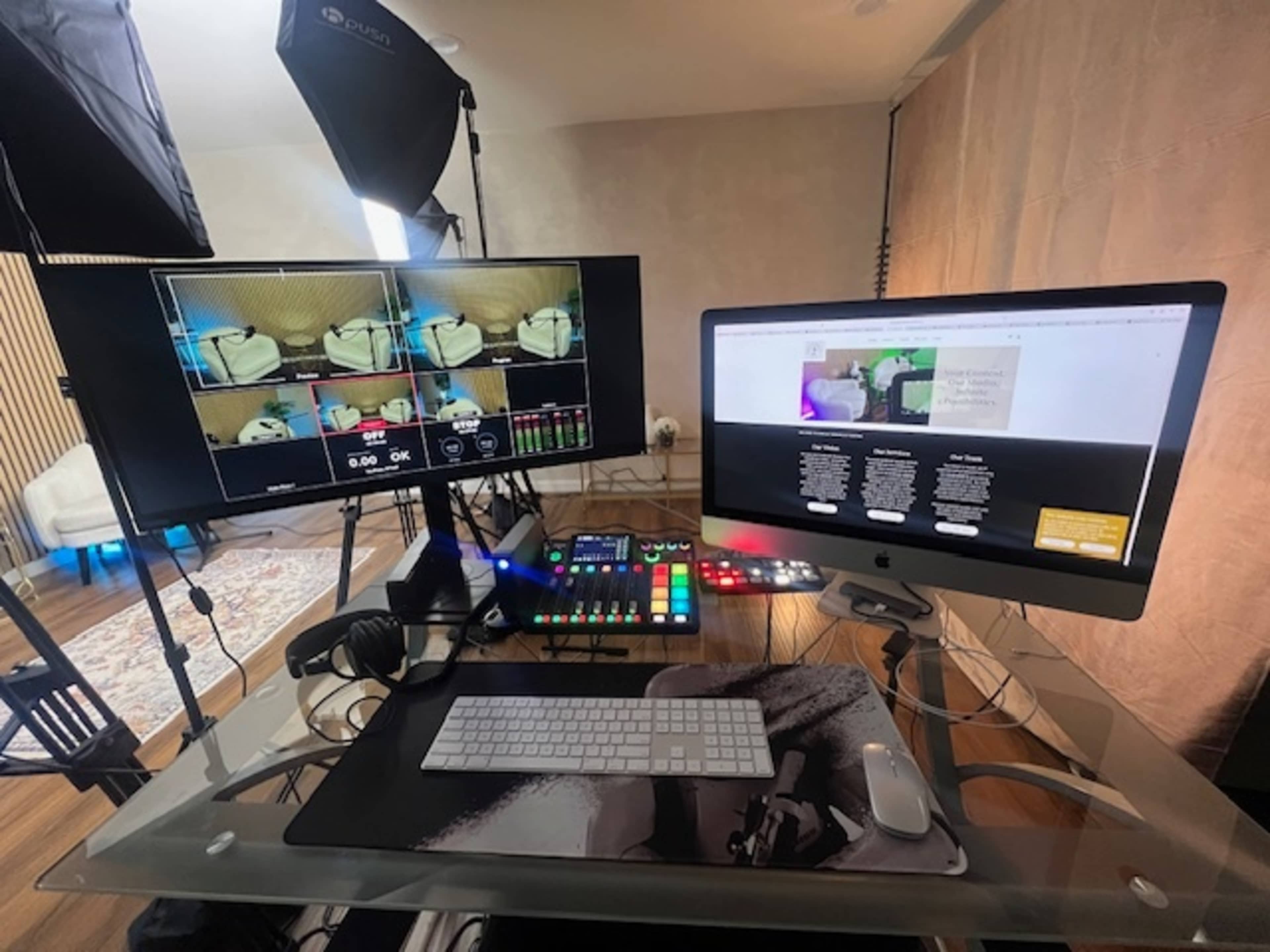 The image shows a modern workspace featuring two screens, a control panel, a keyboard, and various lighting equipment in a well-lit room.