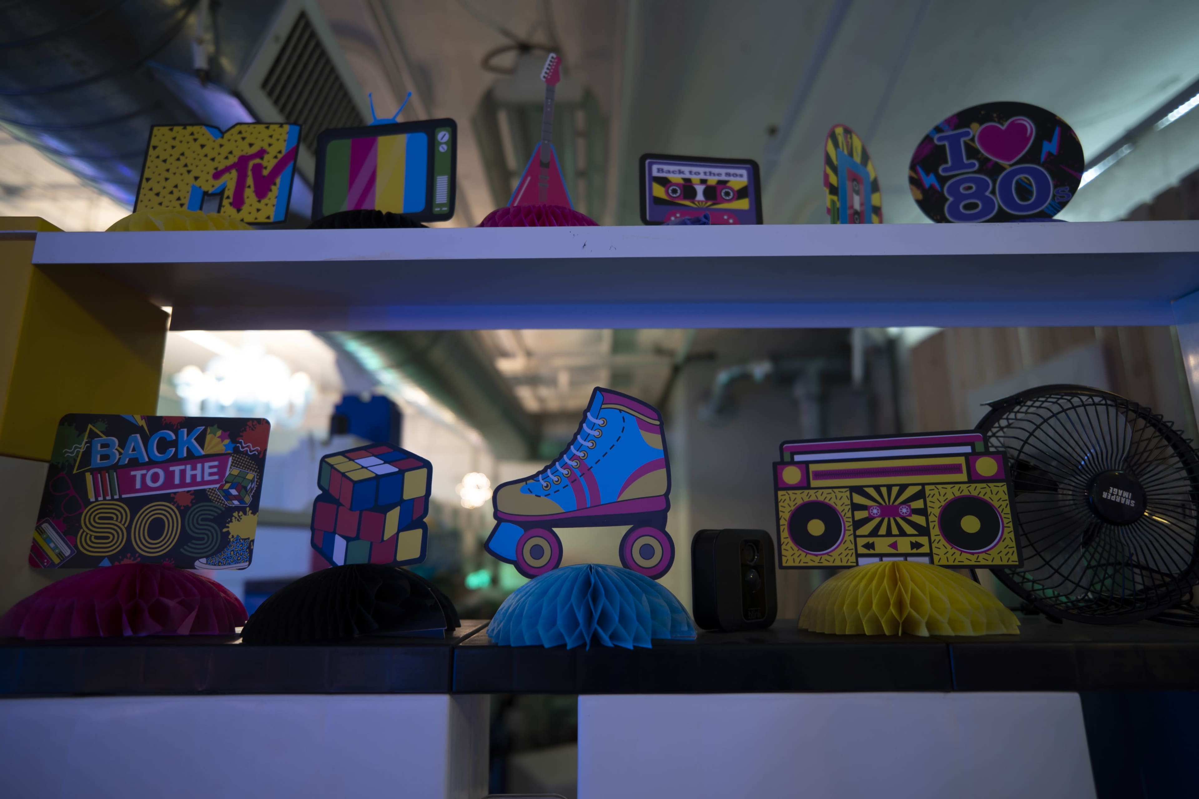 A colorful display of retro-themed decorations on a shelf, including items like a miniature boombox, a roller skate, and a Rubik's cube.