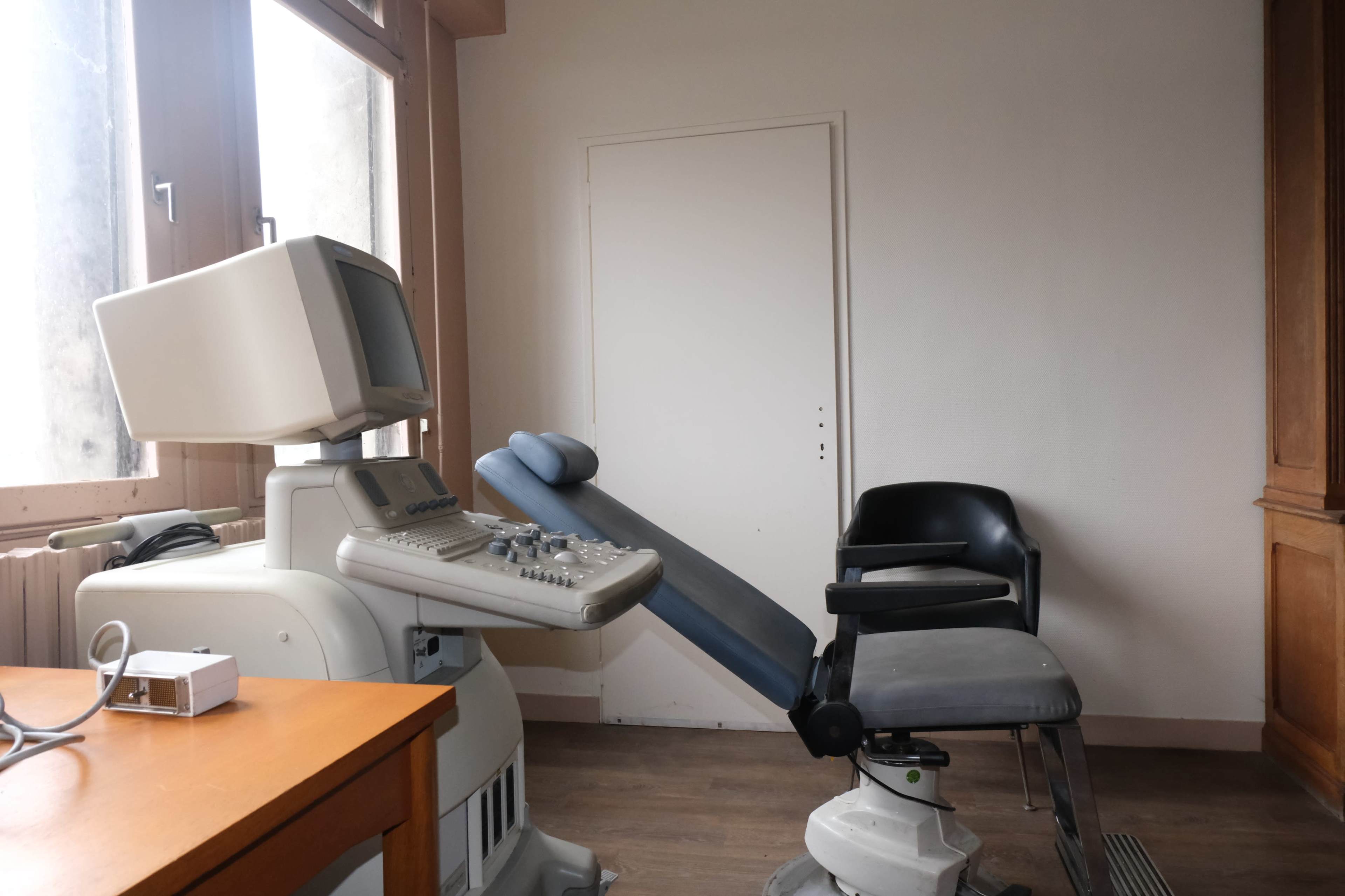 A medical examination room featuring a diagnostic machine and an adjustable examination chair.