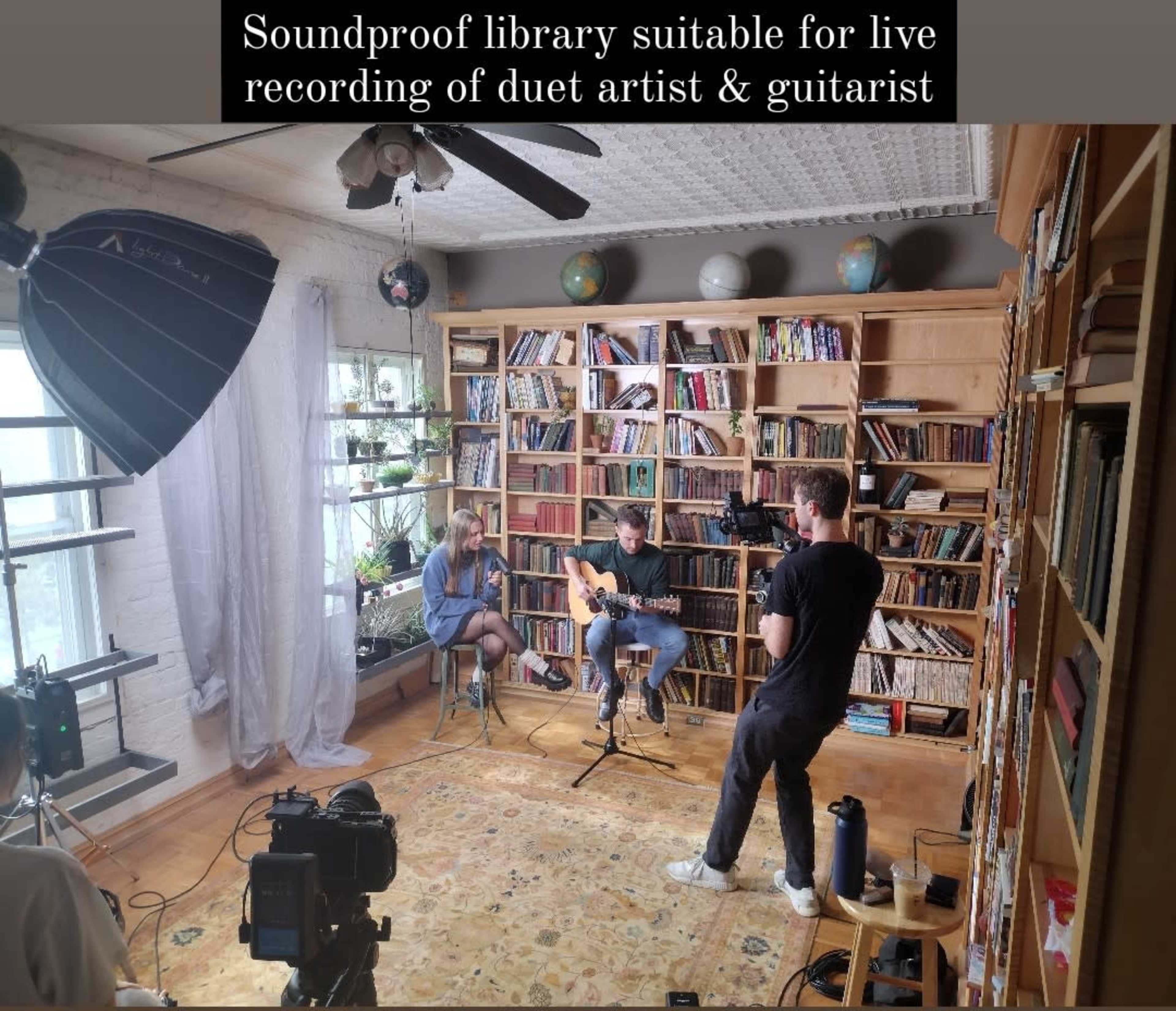 A soundproof library is set up with a duet artist and guitarist, while a videographer captures the performance.