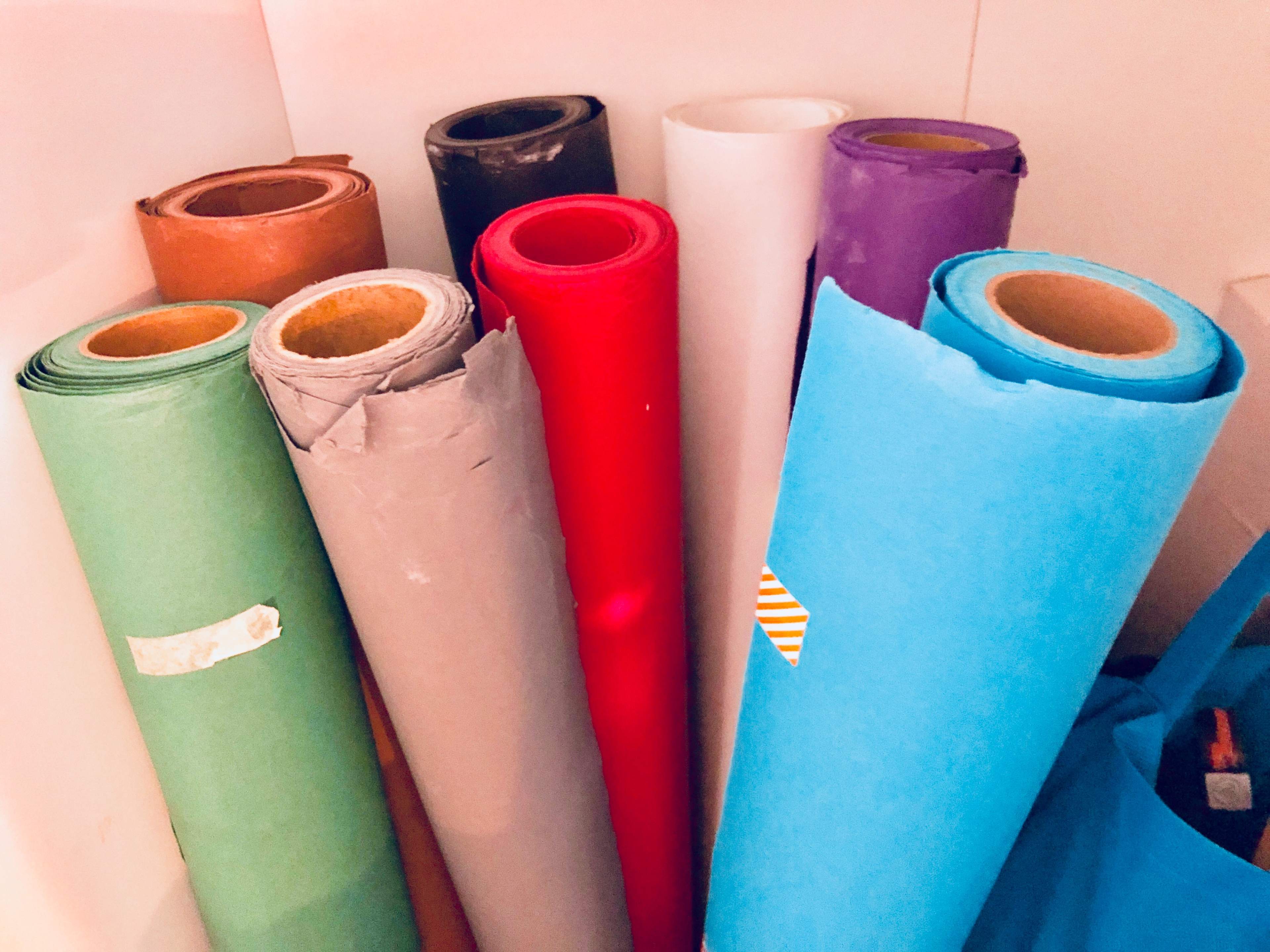A collection of rolled paper in various colors is stacked in a storage space.