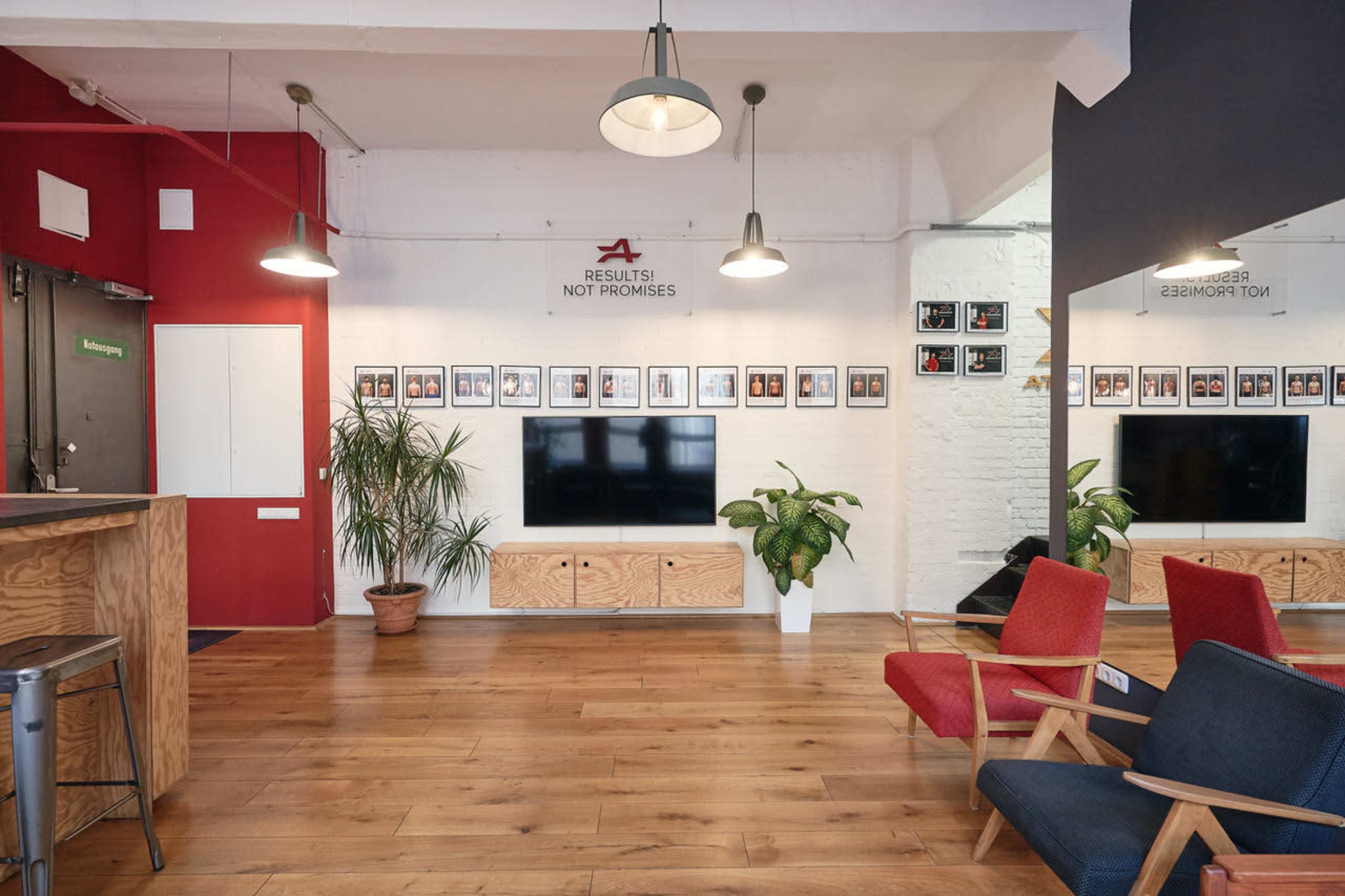 The image shows a modern office reception area with a television, framed photos on the wall, potted plants, and seating arrangements.