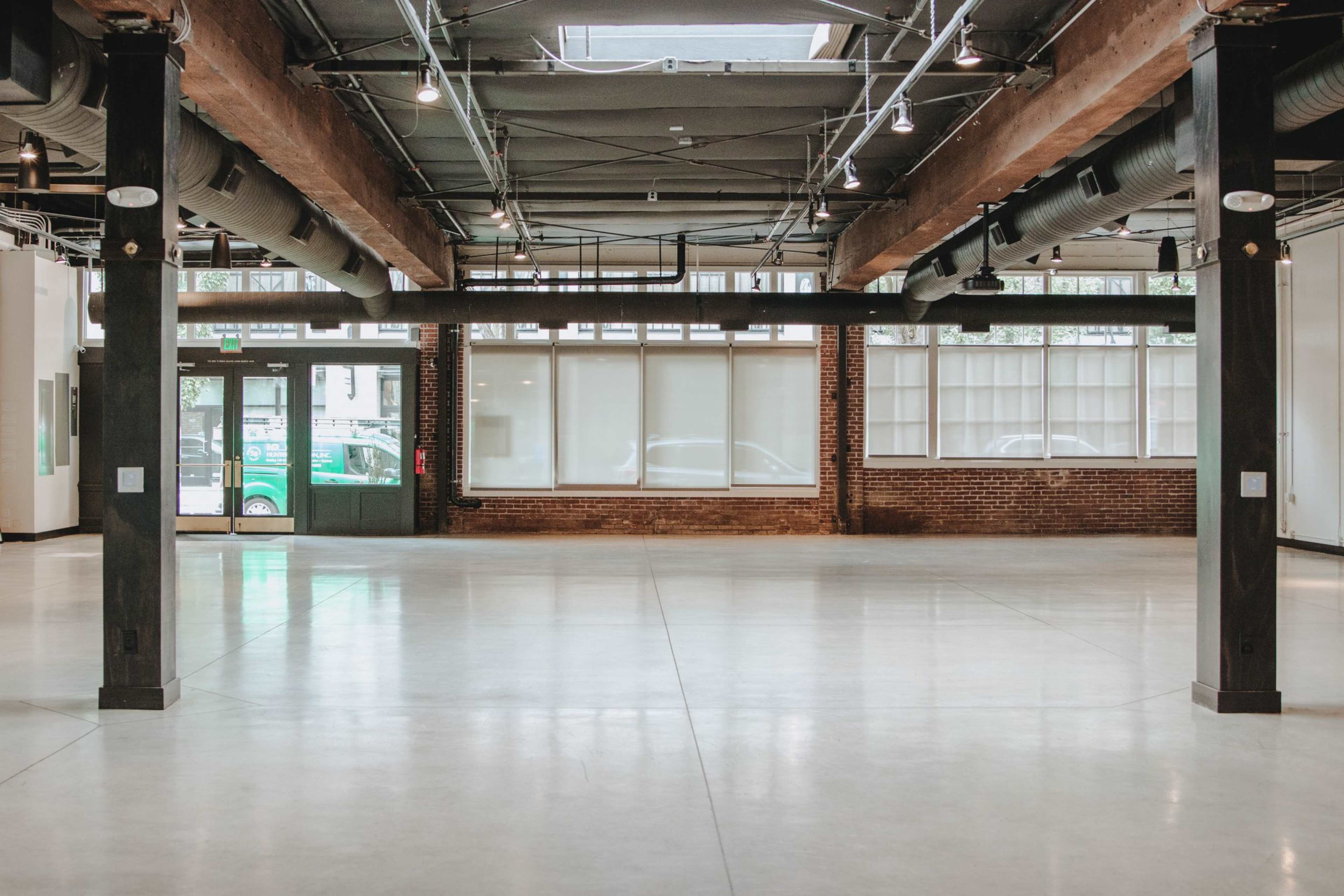 A spacious, empty interior of a modern building featuring large windows and exposed beams.