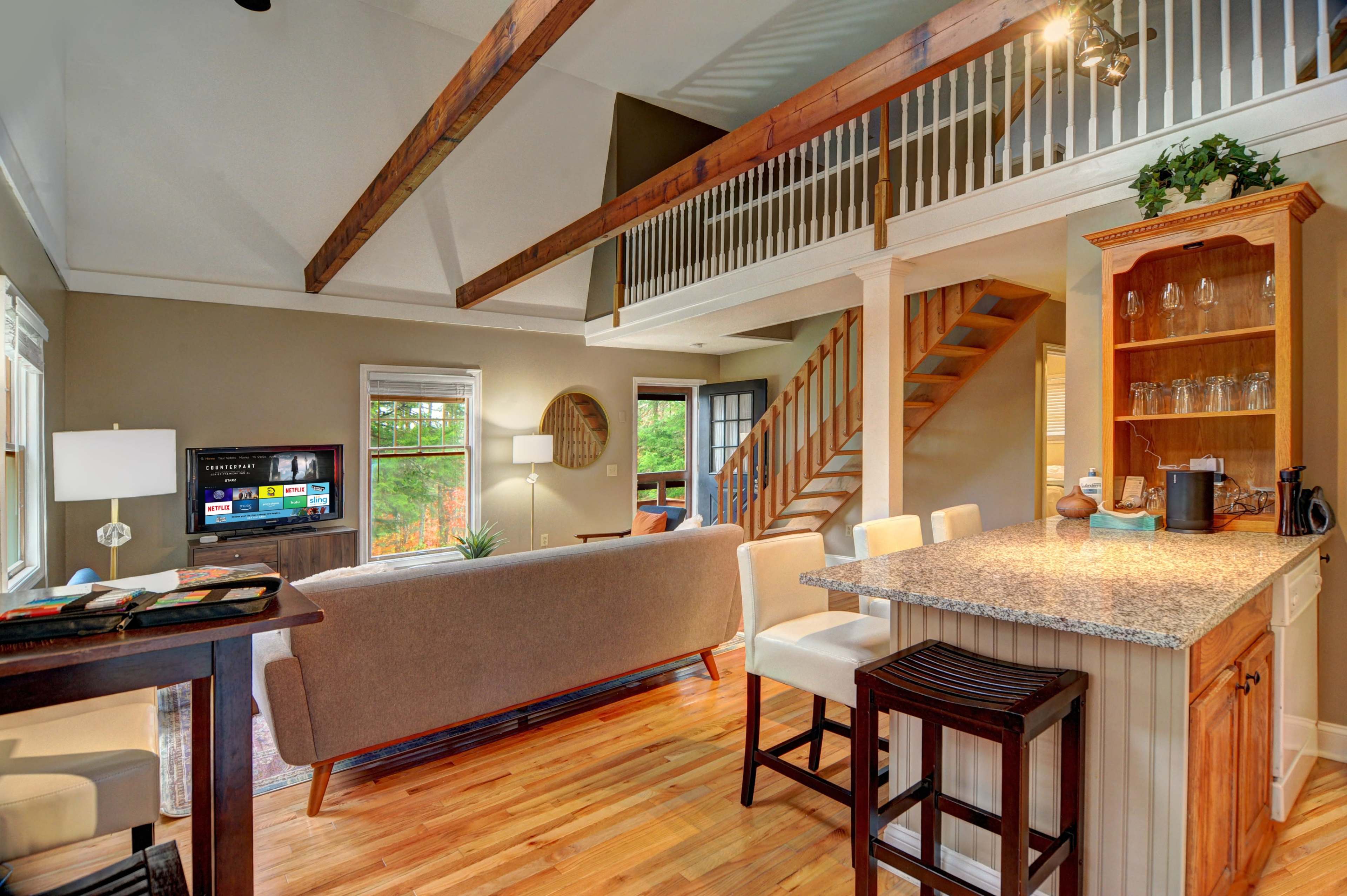A spacious living area with a view of a kitchen bar, a couch, and a staircase leading to an upper level.