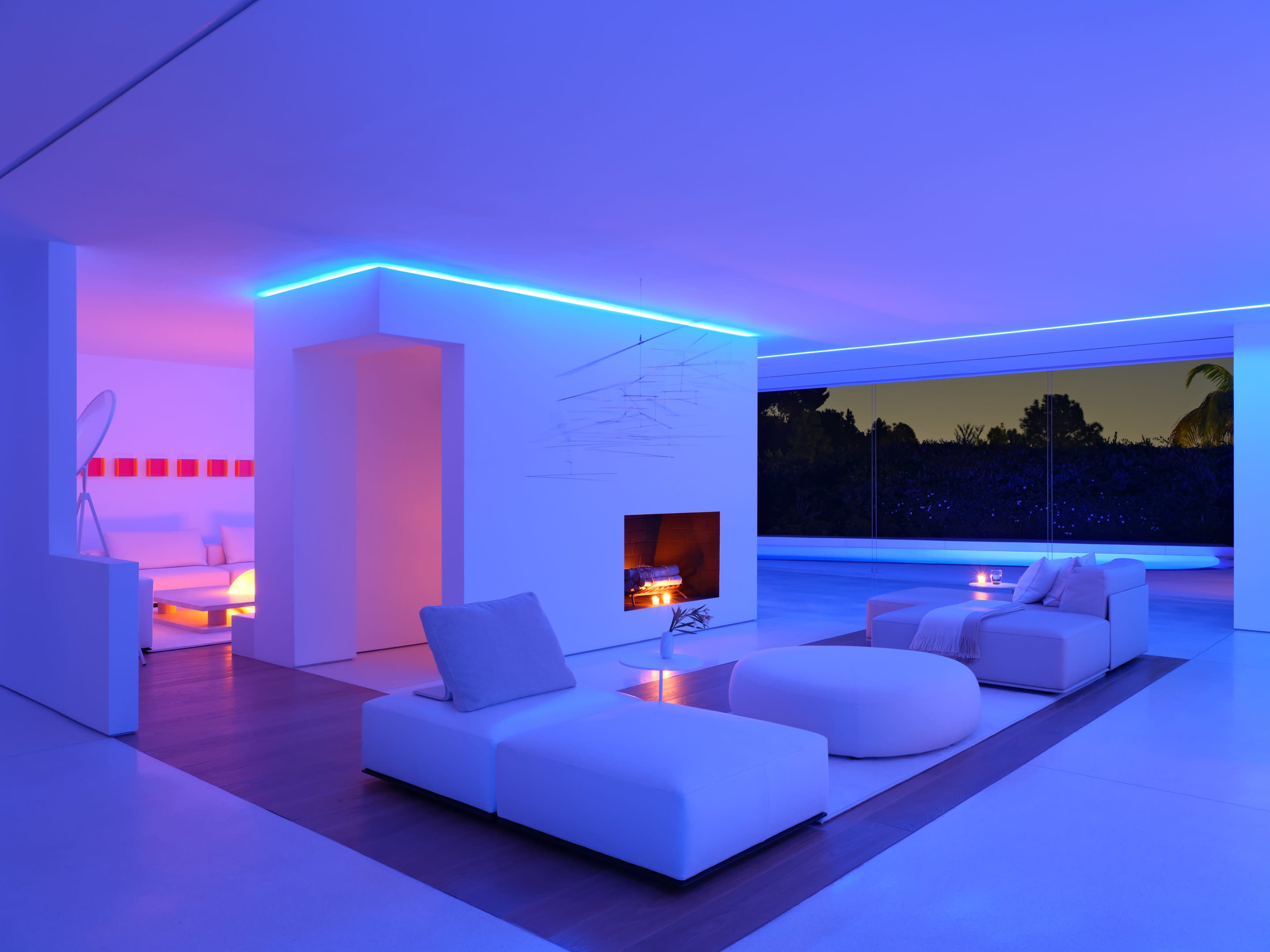 A modern living room features sleek white furniture, ambient lighting, and a glass wall overlooking a pool.
