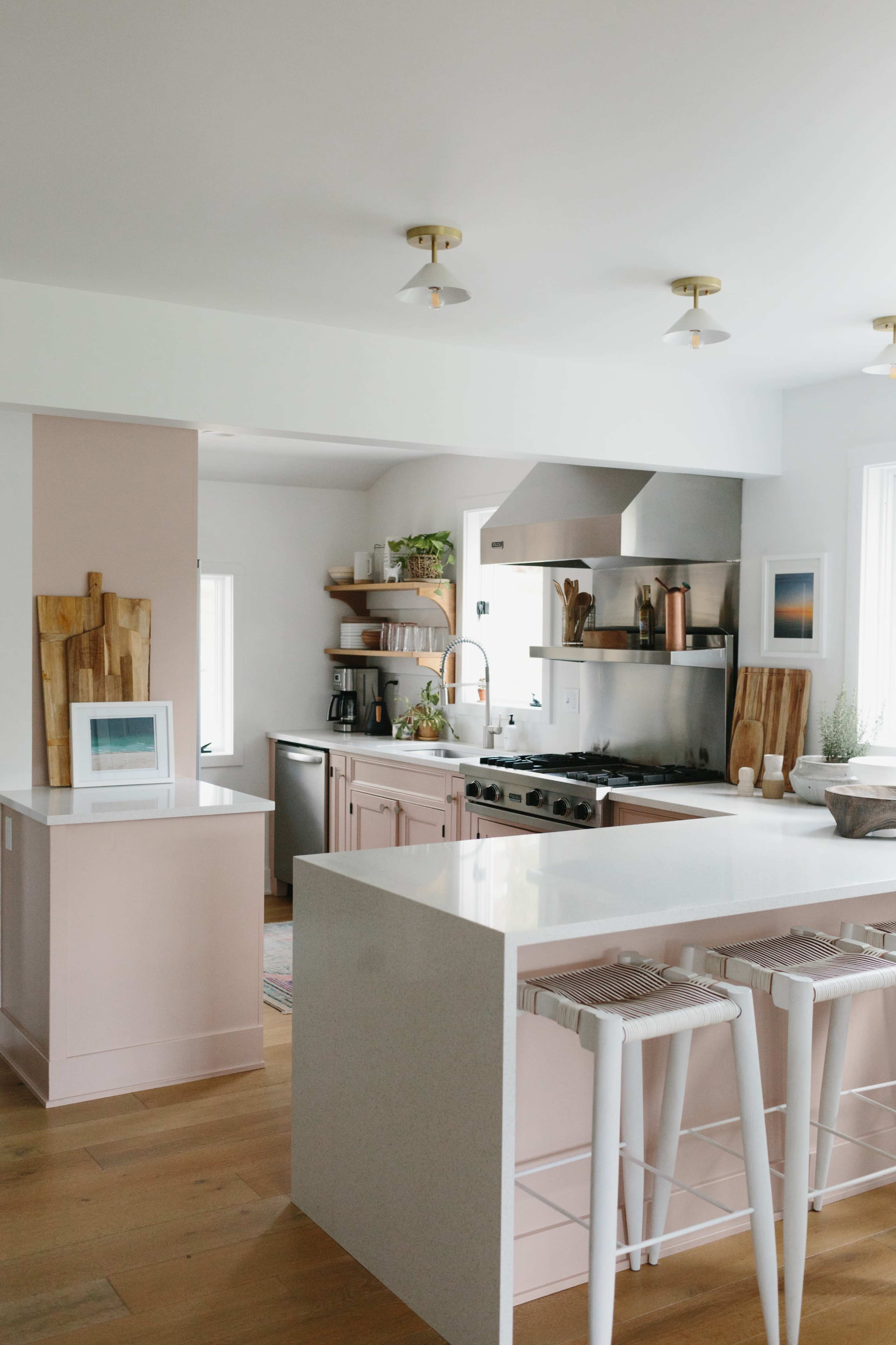 A modern kitchen with a central island, stainless steel appliances, and light-colored cabinetry.