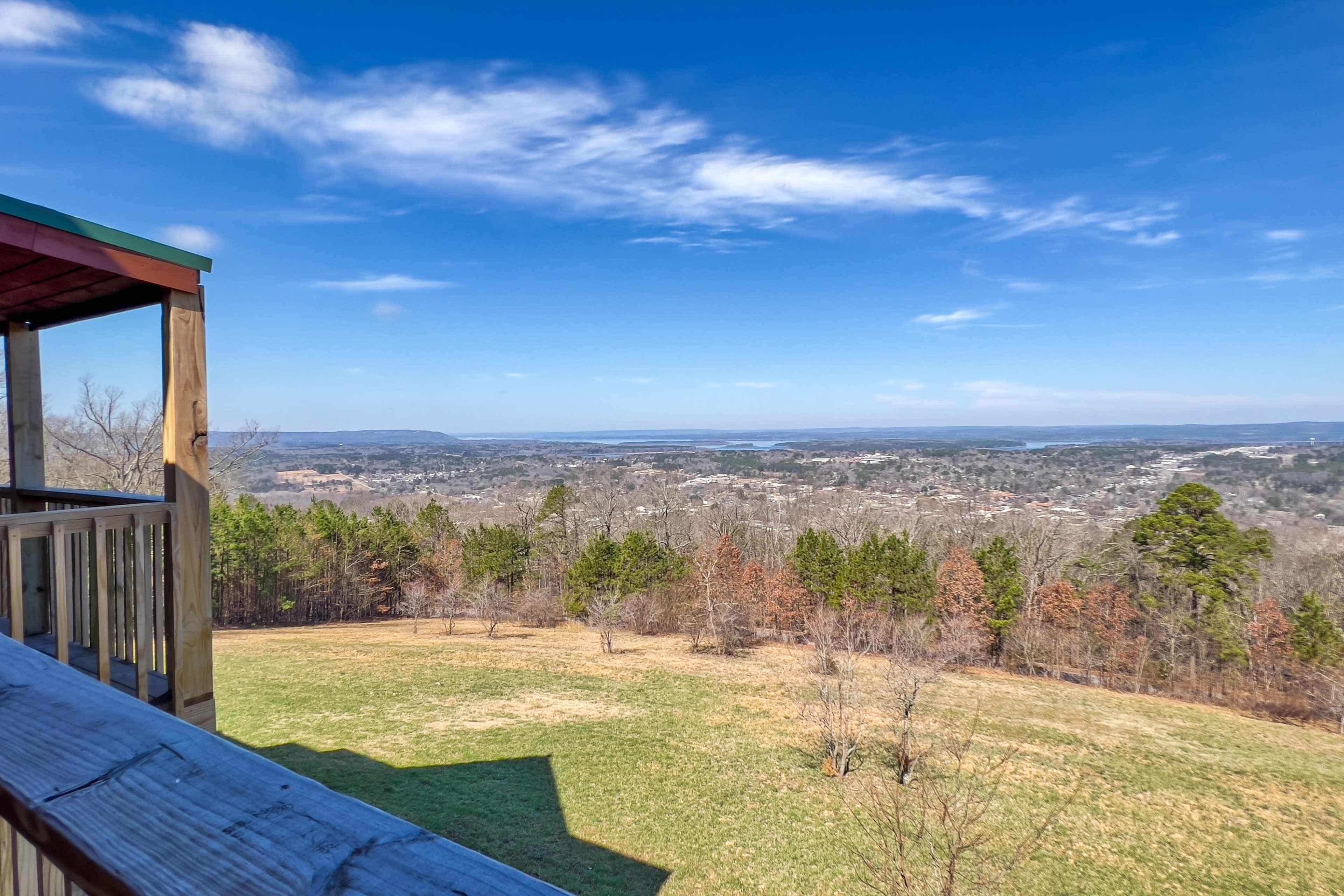 A panoramic view of a valley with scattered trees and a distant horizon under a clear blue sky.