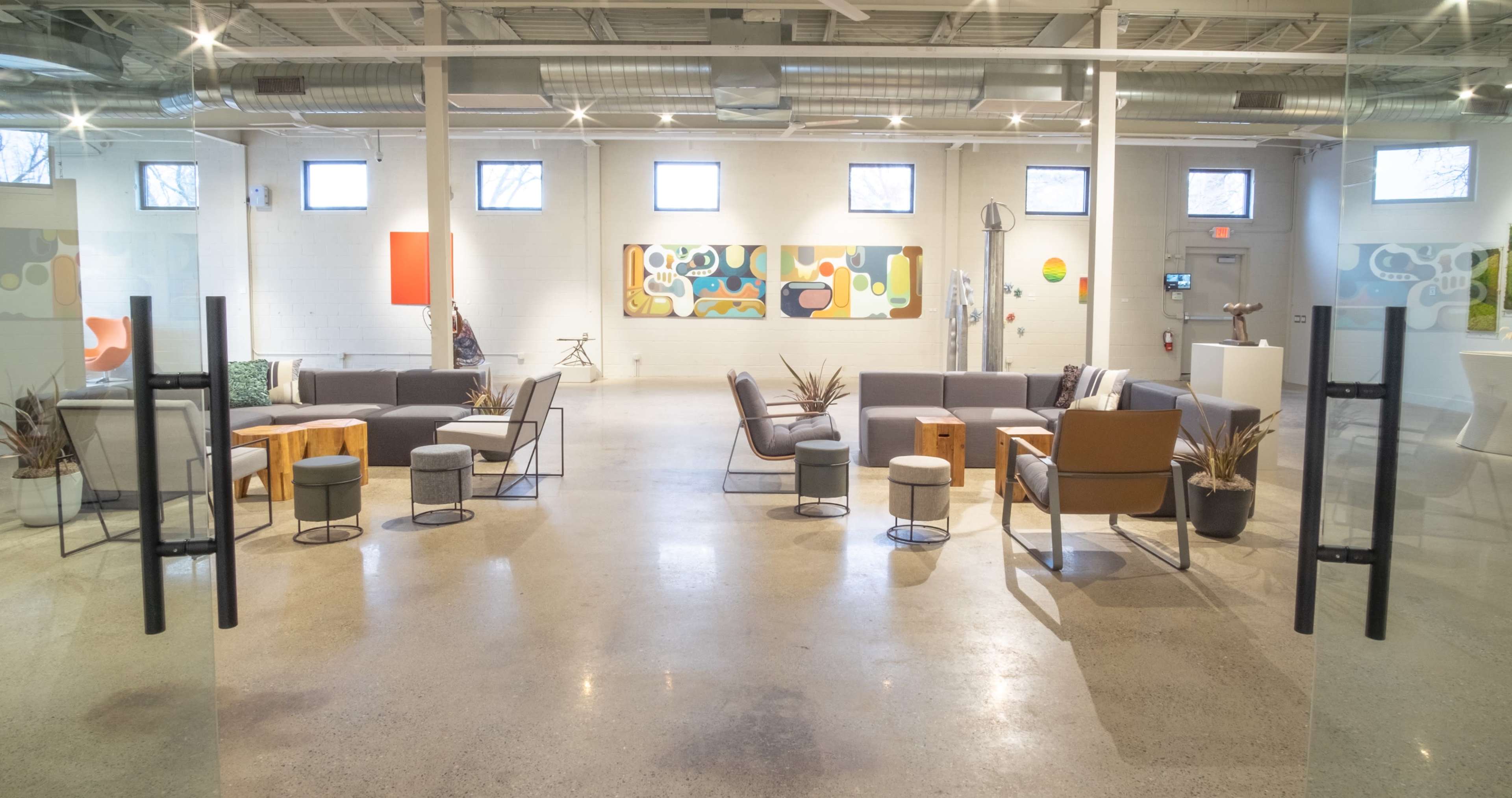 The image shows a spacious, modern lounge area with several seating arrangements, art on the walls, and various decorative elements.