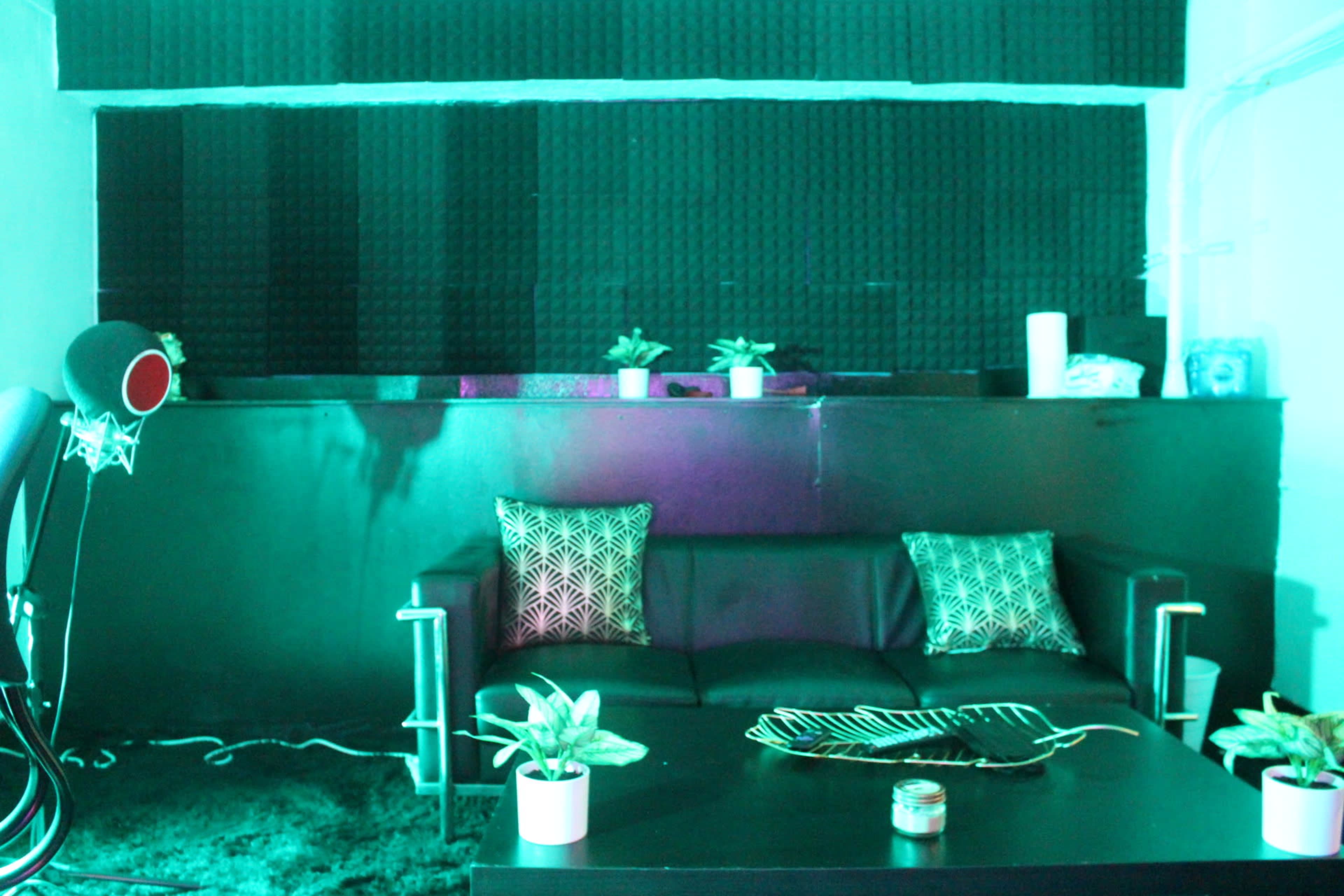 A modern lounge area with a black couch, decorative pillows, a coffee table with a decorative tray, and a textured wall behind it.