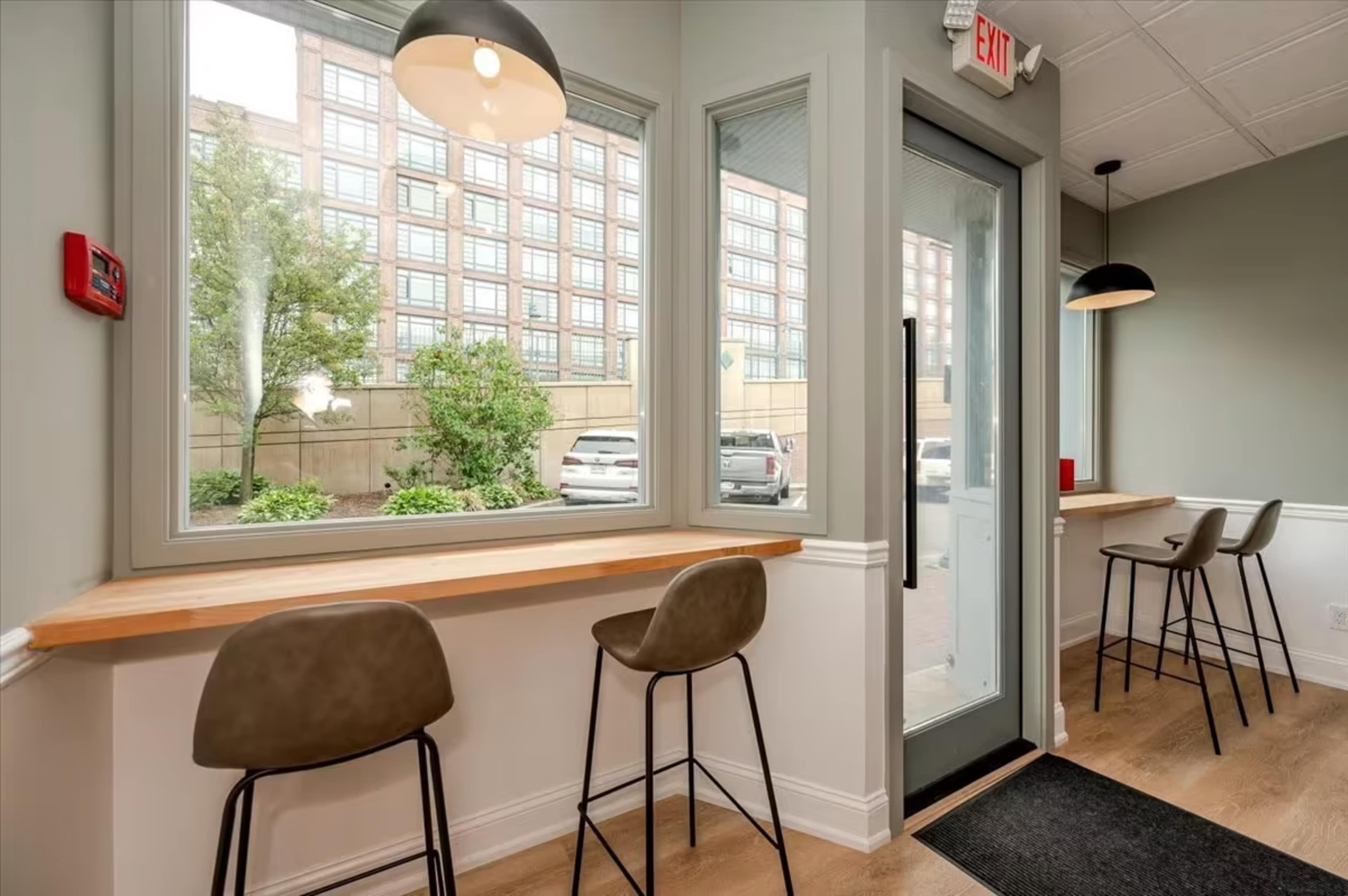 A modern interior with seating areas beside large windows overlooking an outdoor parking area.