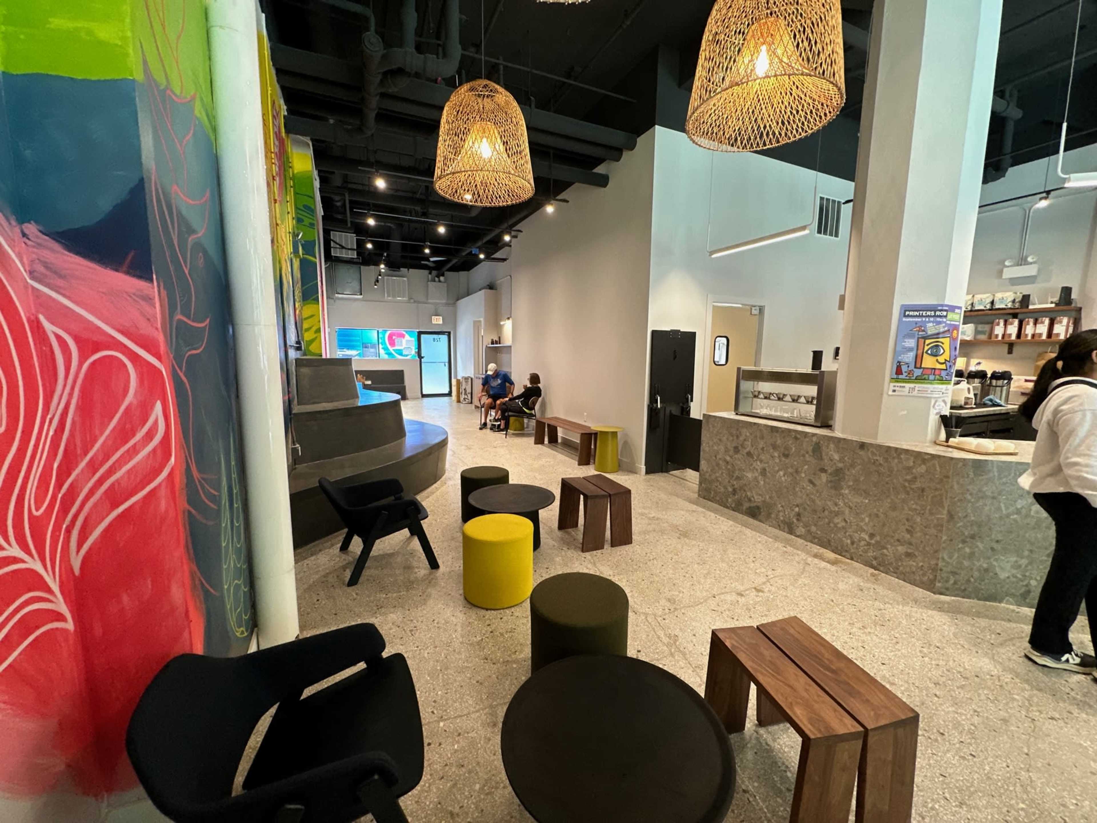 A modern indoor space with colorful wall art, various seating arrangements, and a service counter.
