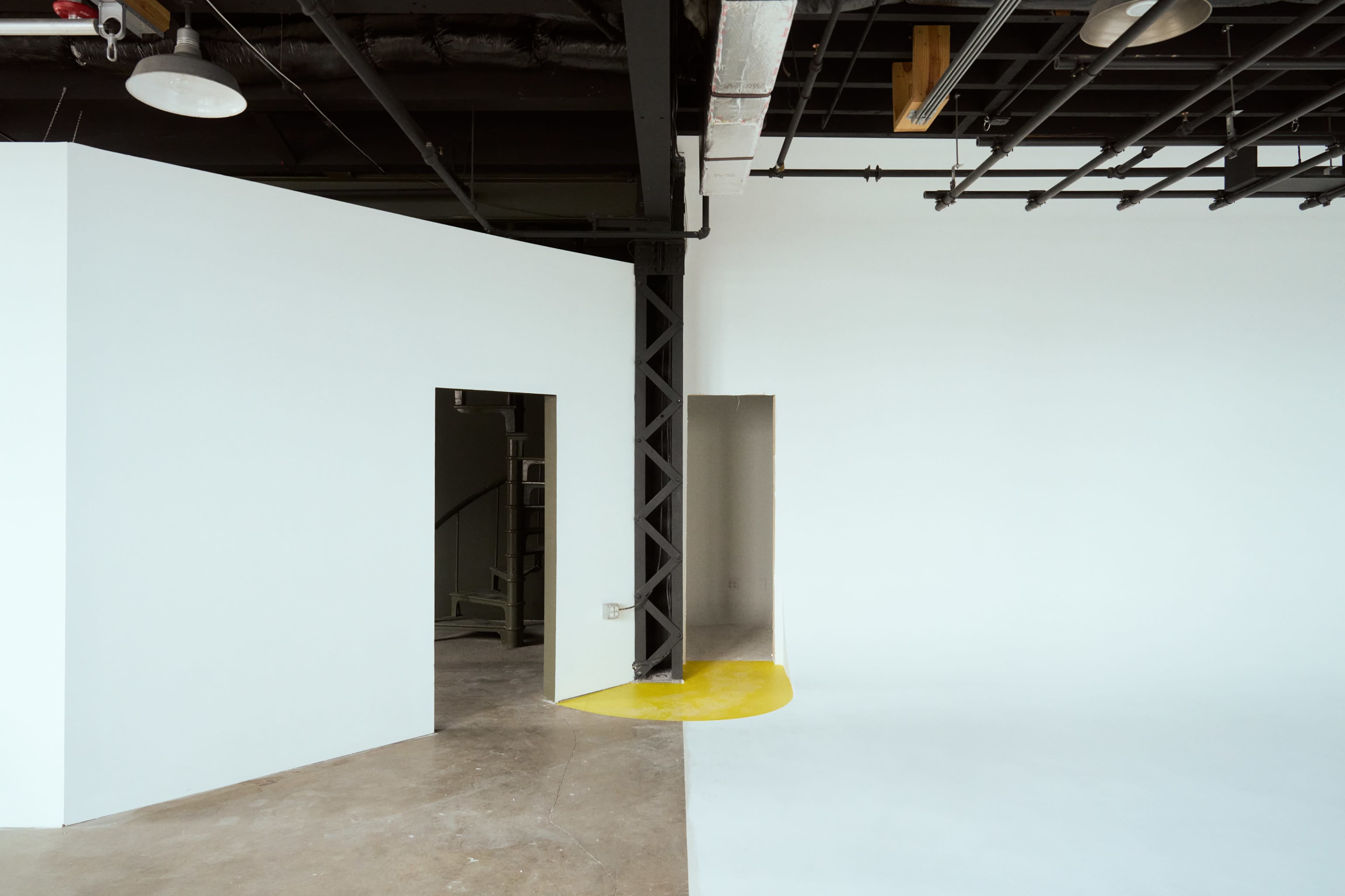 An interior space with white walls, two doorways, and a yellow floor area.