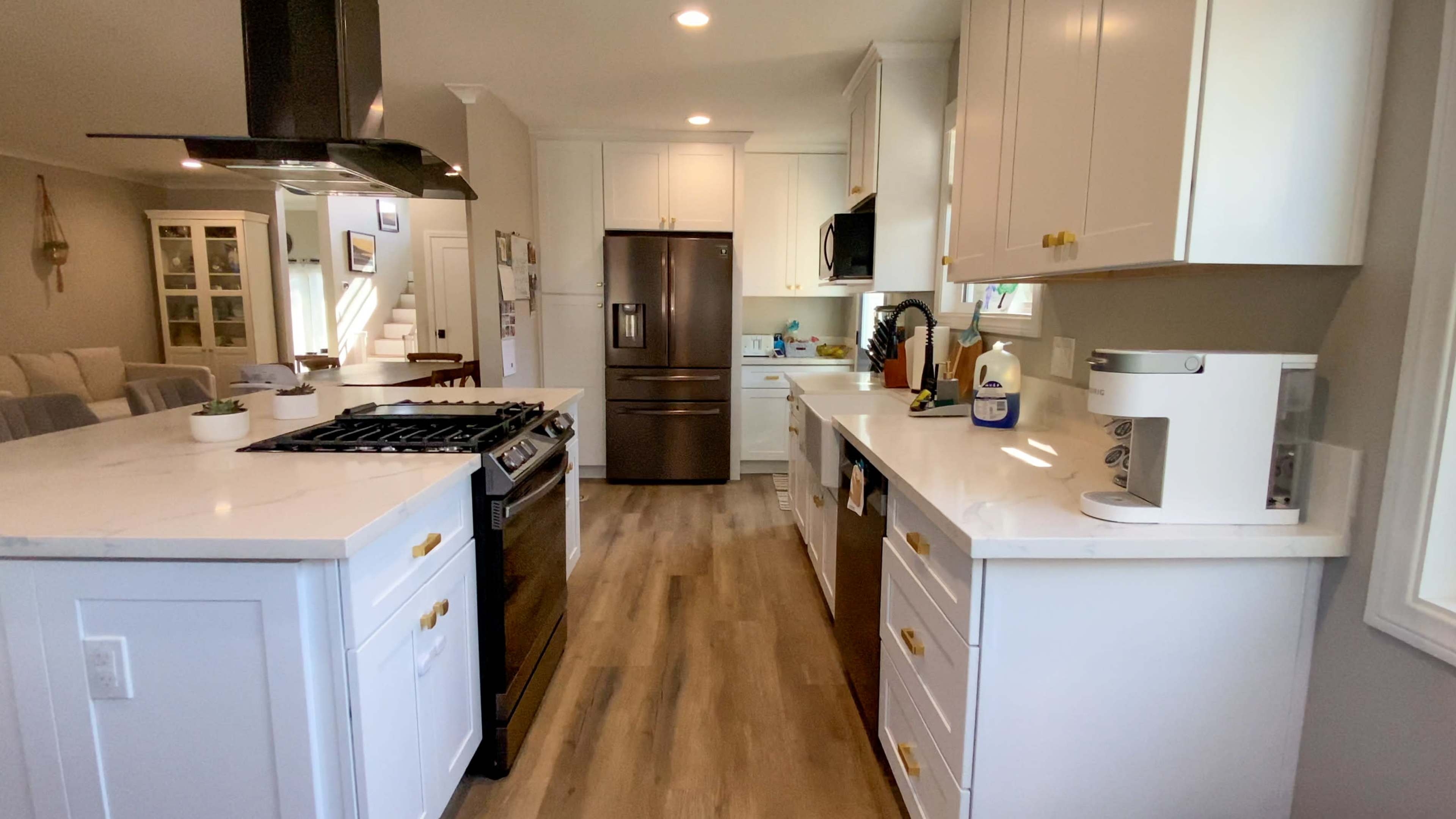 A modern kitchen features white cabinetry, stainless steel appliances, and a central island with a gas stove.