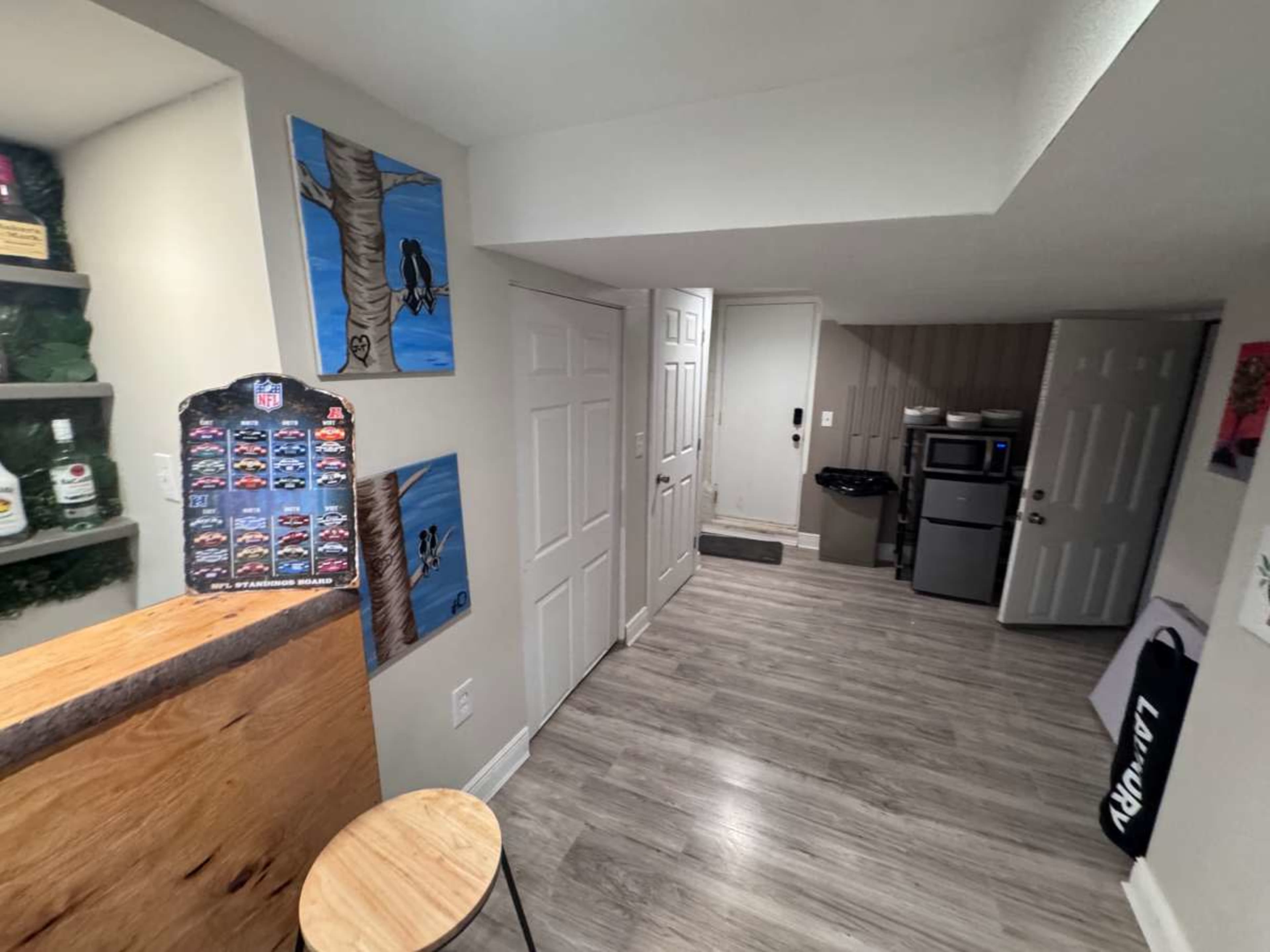 The image shows a well-lit interior space with a small kitchenette, including a mini refrigerator and a microwave, and artwork displayed on the wall.