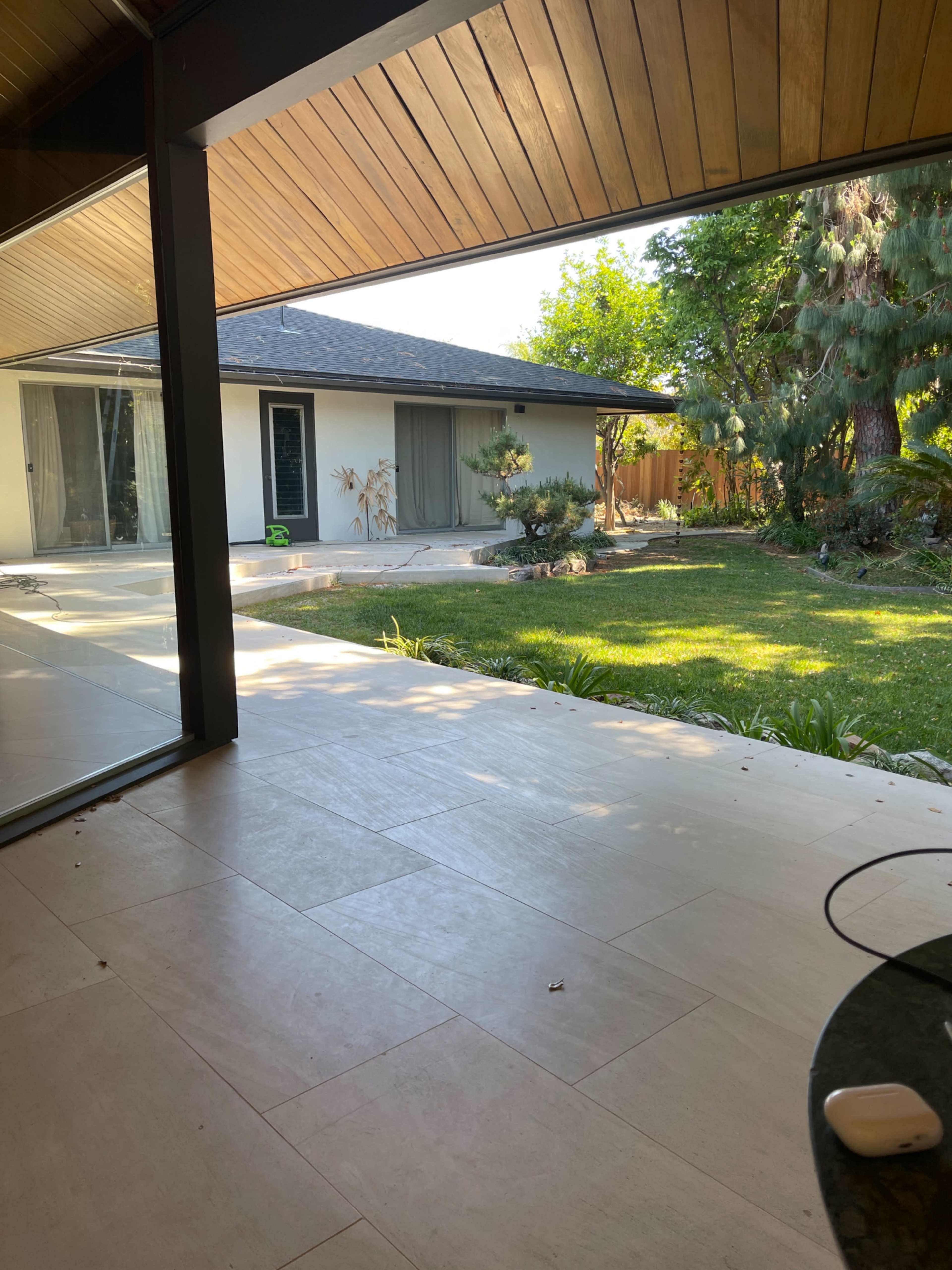 A view from inside a house overlooking a landscaped backyard with grass and trees.