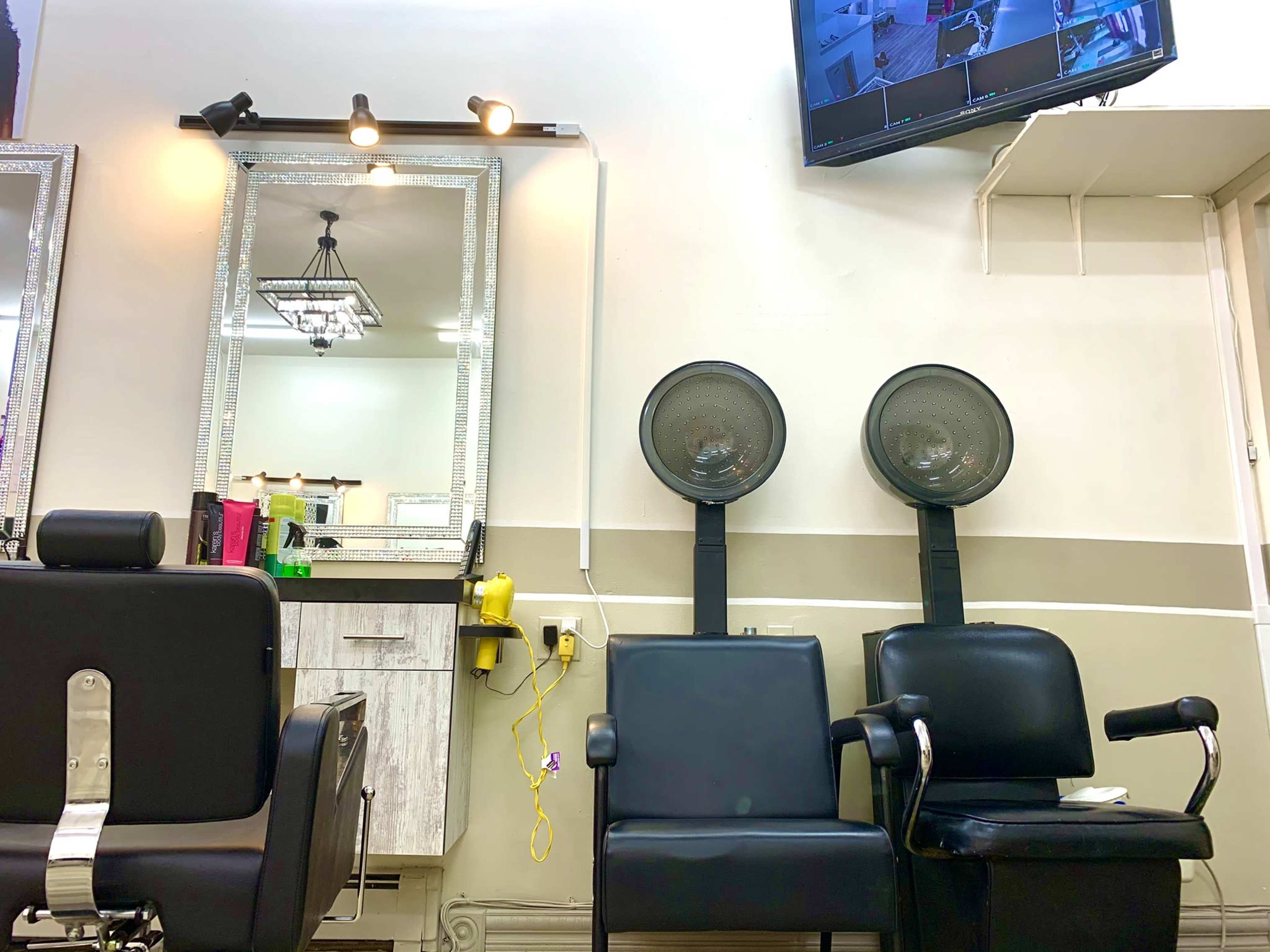 A hair salon interior with styling chairs, a mirror, and two hooded hair dryers mounted on stands.