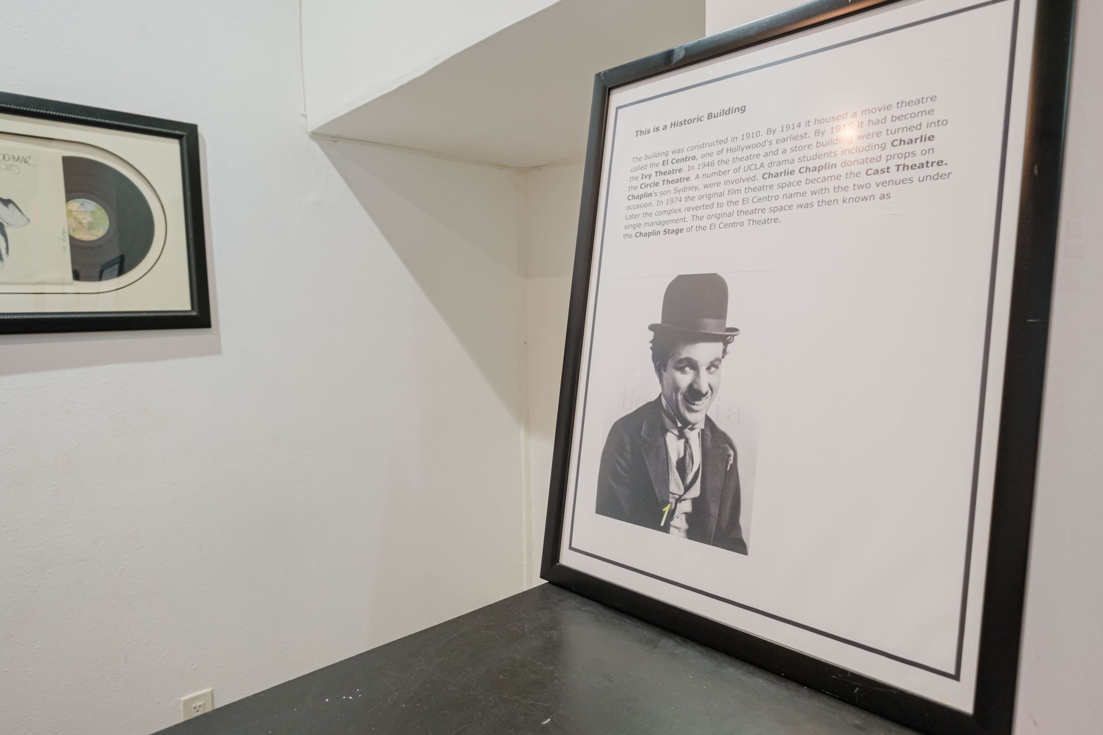 A framed informational plaque about a historic building that once hosted a movie theater, featuring an image of Charlie Chaplin.
