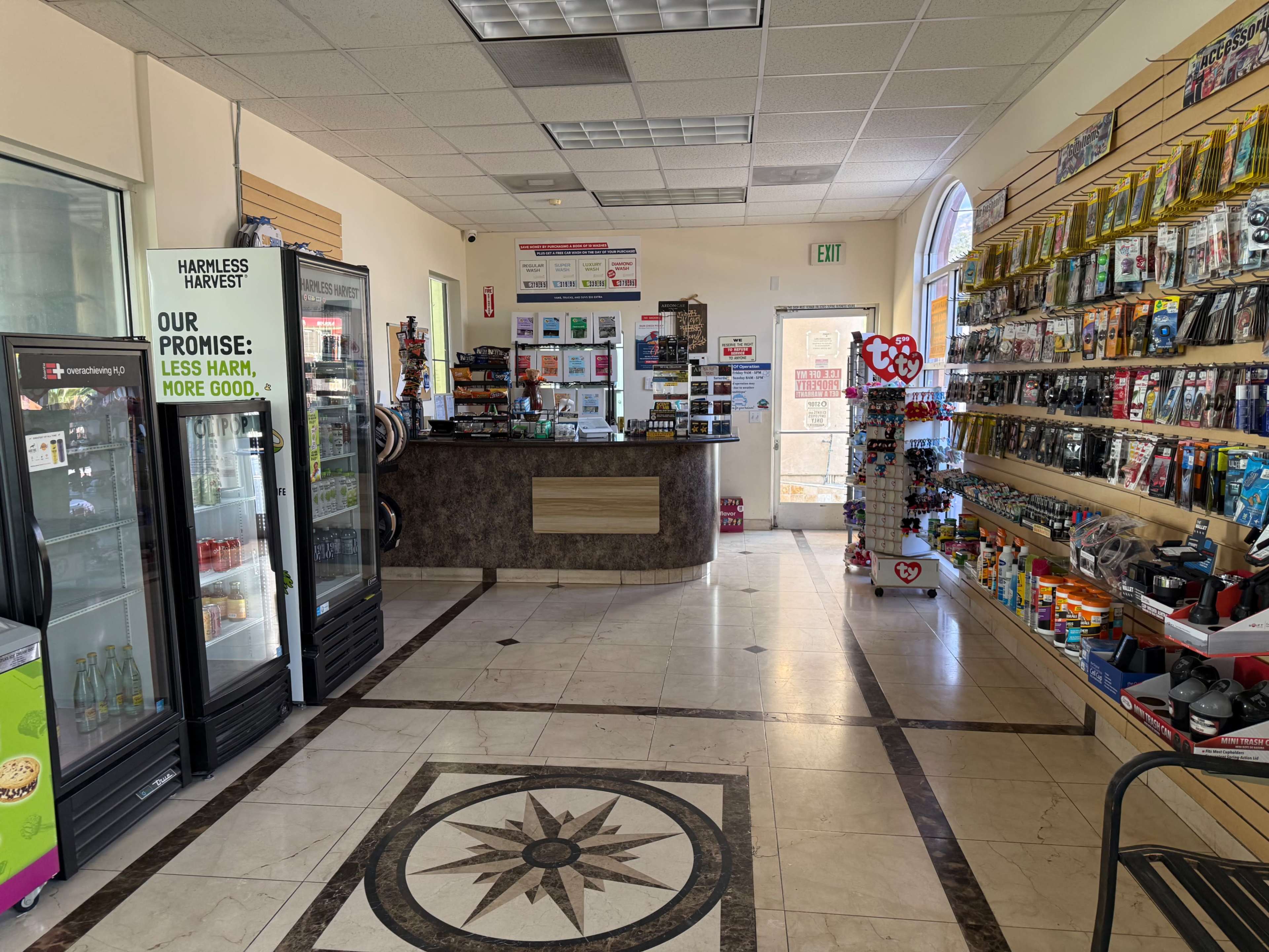 The image shows an interior view of a convenience store with a checkout counter, shelves stocked with various products, and a refrigerated display case.