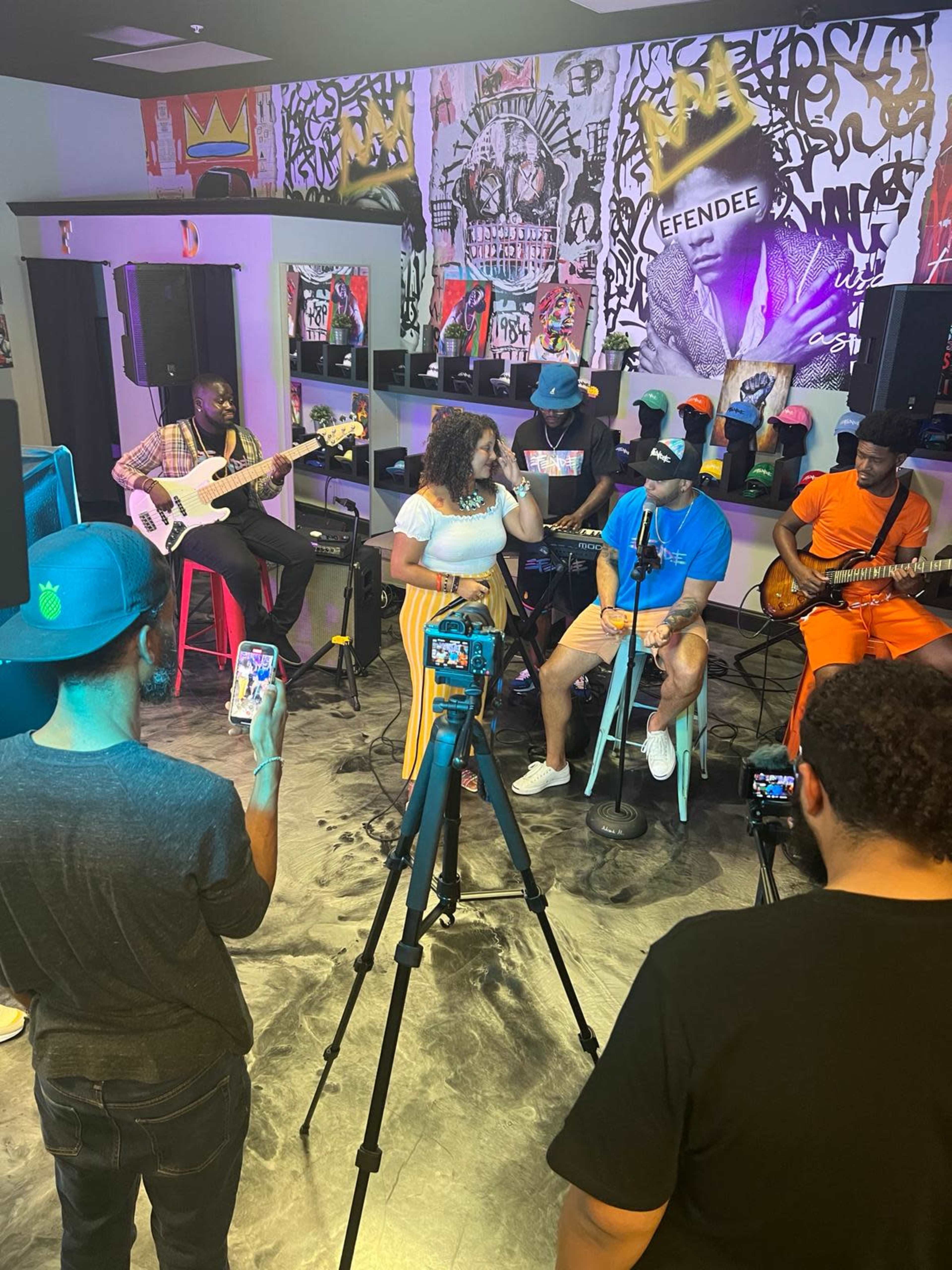 A group of musicians performs on stage while several audience members capture the moment with their smartphones.