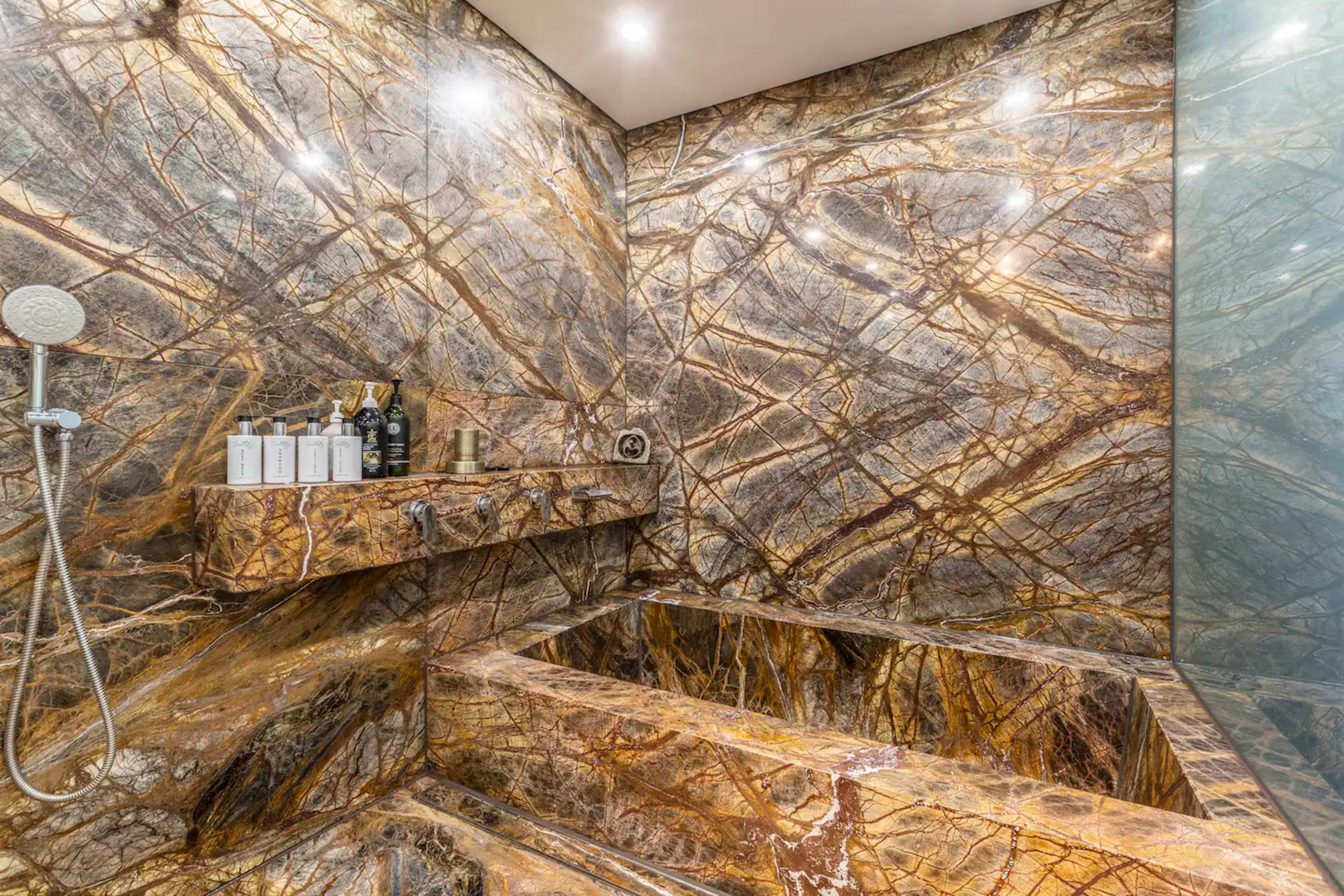 A luxurious bathroom with walls and a tub made of intricate, polished stone featuring bold, swirling patterns.