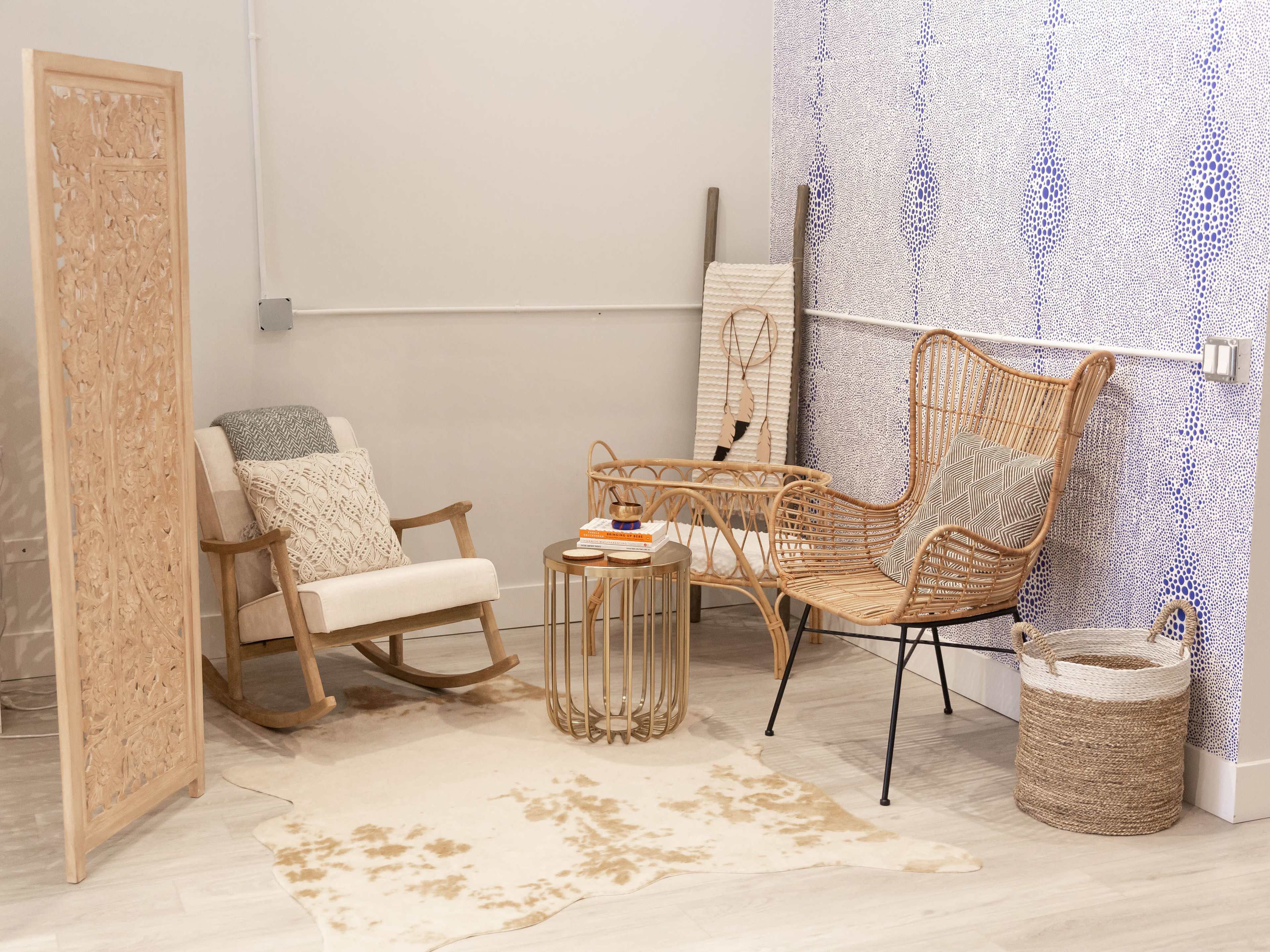 The scene features a cozy corner with a rocking chair, a rattan chair, a round glass table, and a decorative screen, all arranged on a patterned rug.