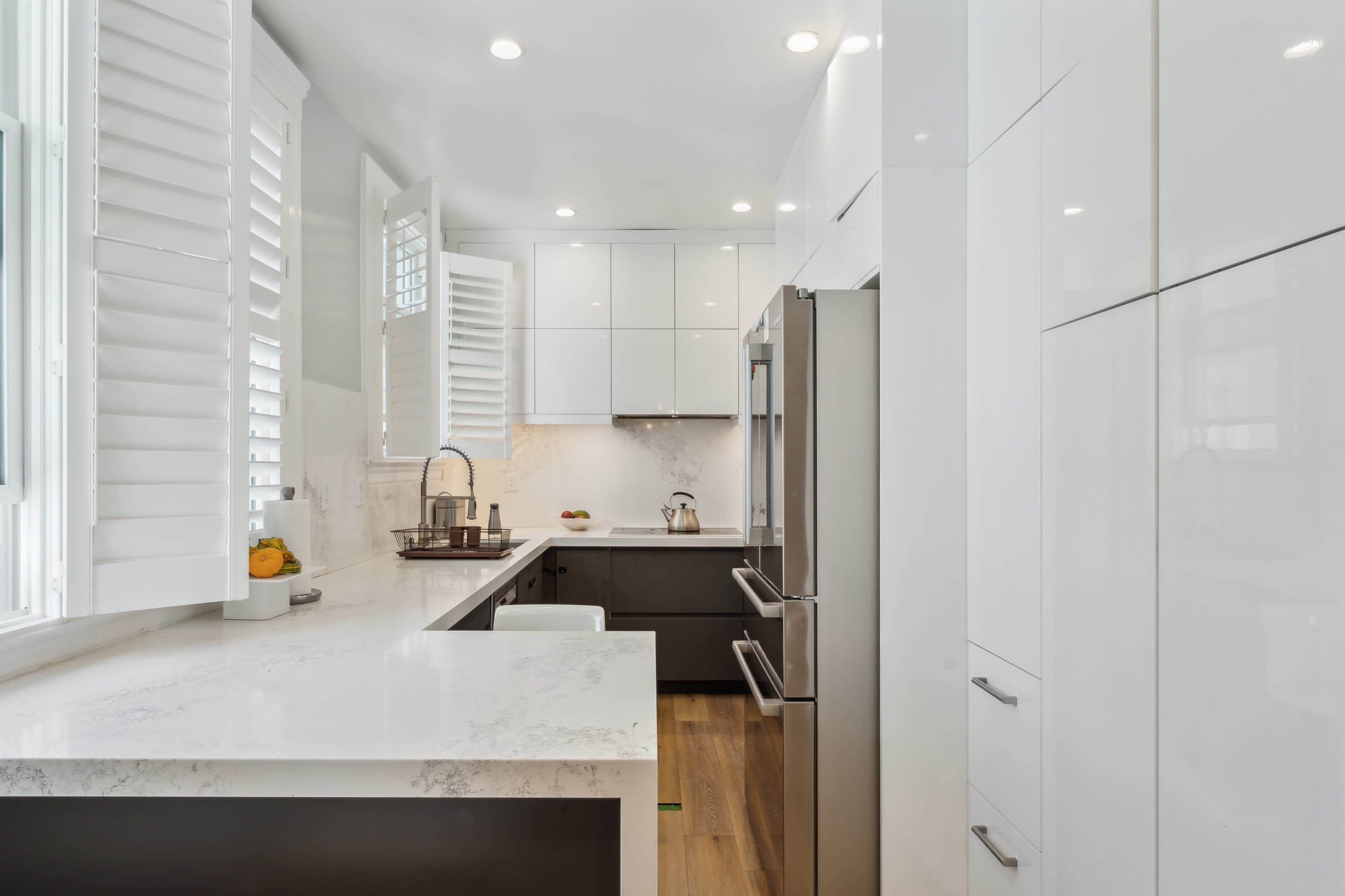 A modern kitchen with white cabinetry, a marble countertop, and stainless steel appliances.