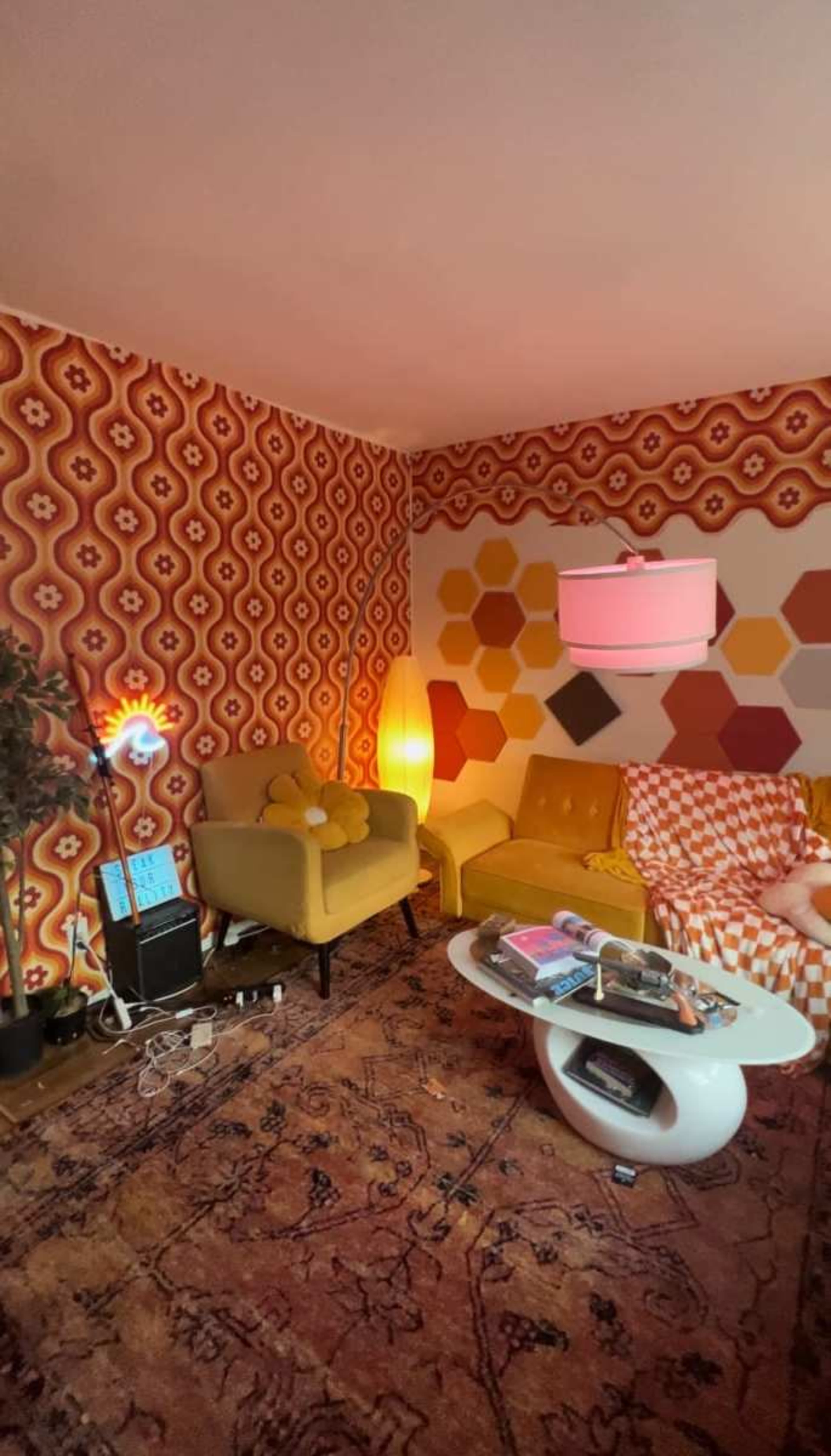 A retro-styled living room with patterned walls, a yellow couch, and a round coffee table.