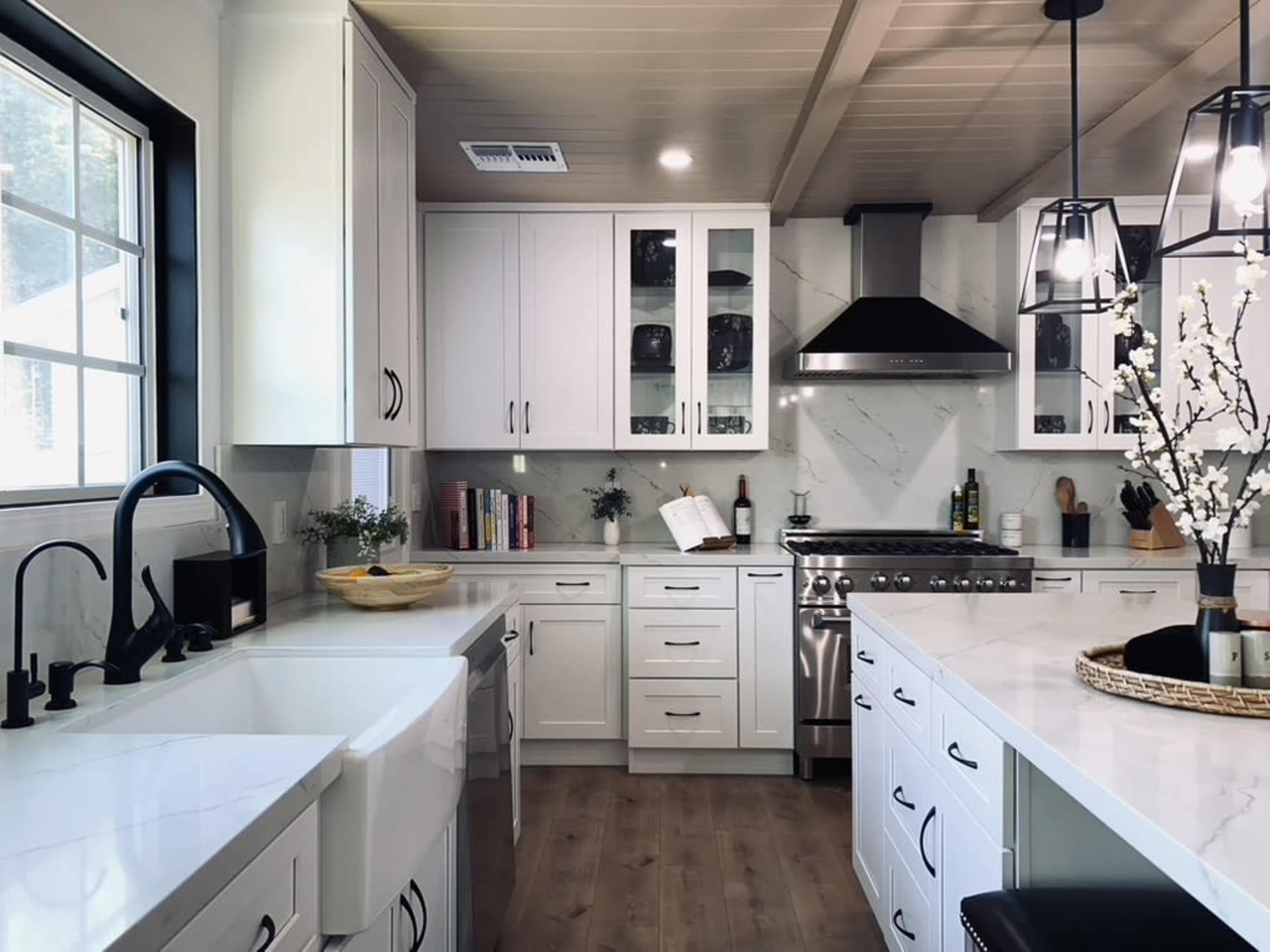 A modern kitchen features white cabinetry, marble countertops, and stainless steel appliances.