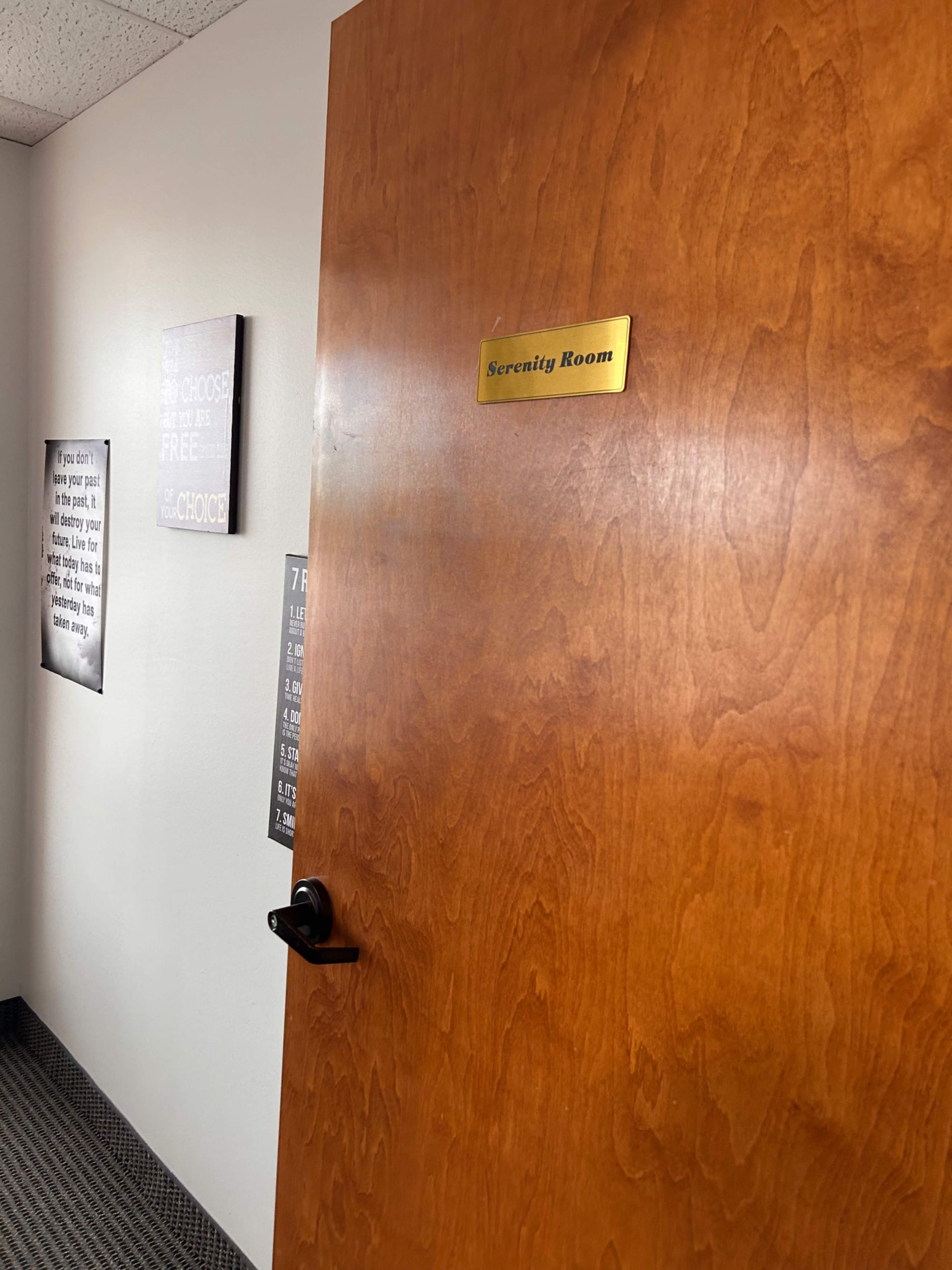 The image shows a wooden door labeled "Serenity Room" with adjacent signs on the wall containing text.