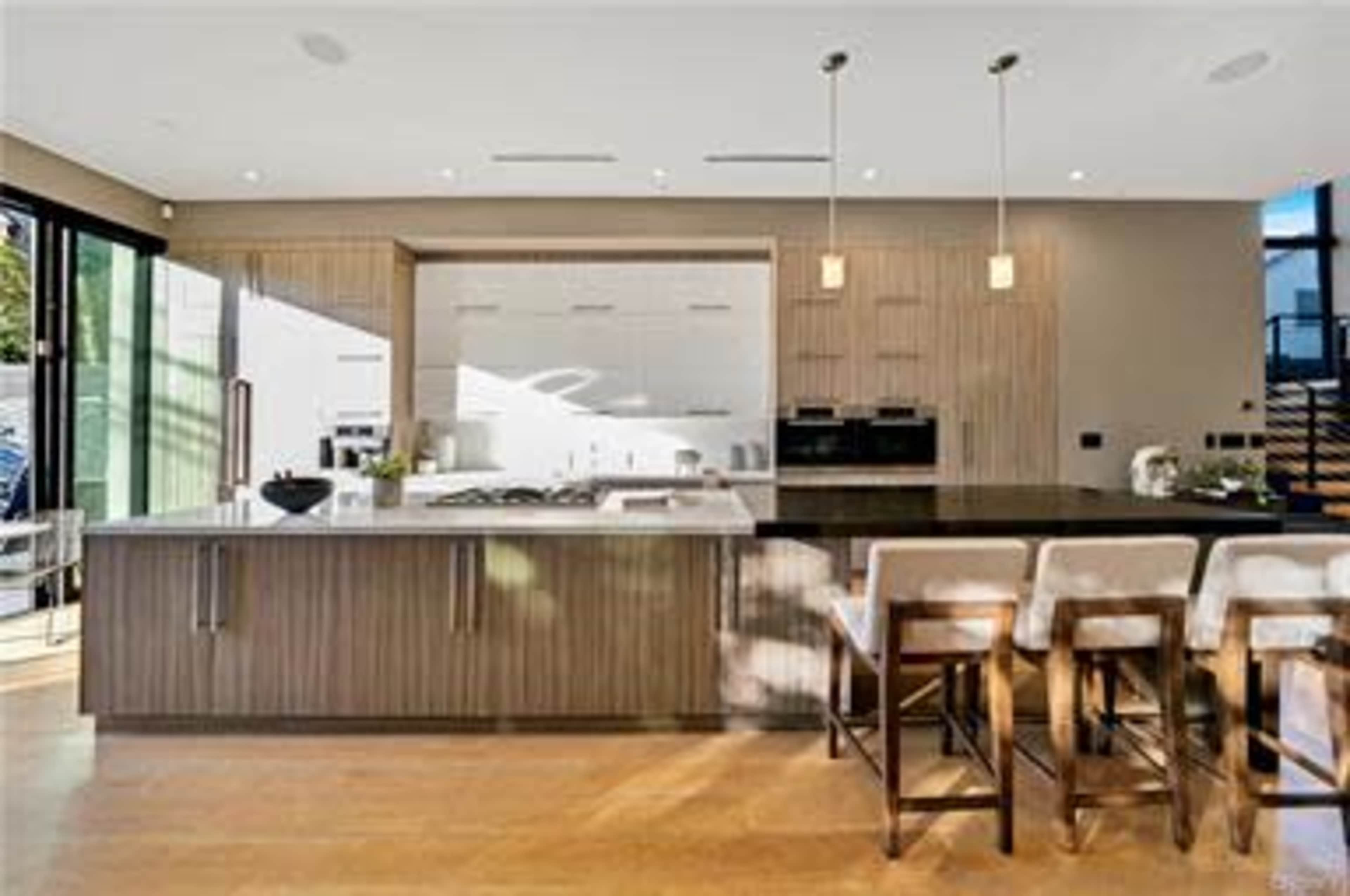 The kitchen features a central island with bar seating, modern appliances, and a minimalist design.